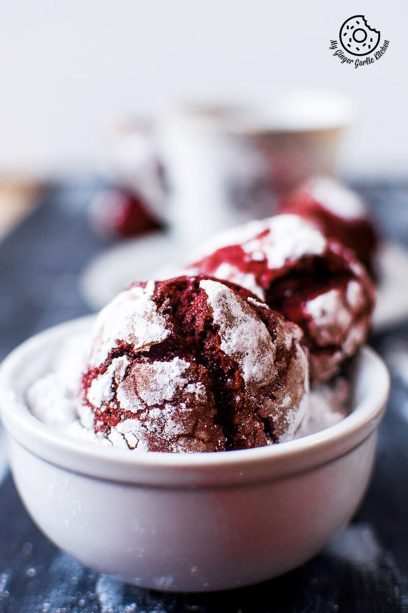 red velvet crinkle cookies are in a white sugar bowl