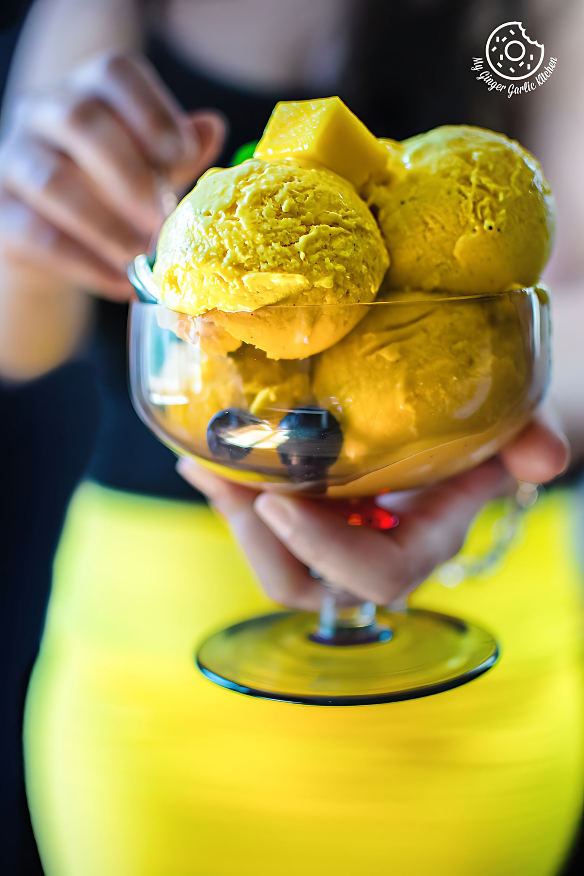 female holding a dessert glass with frozen mango yogurt