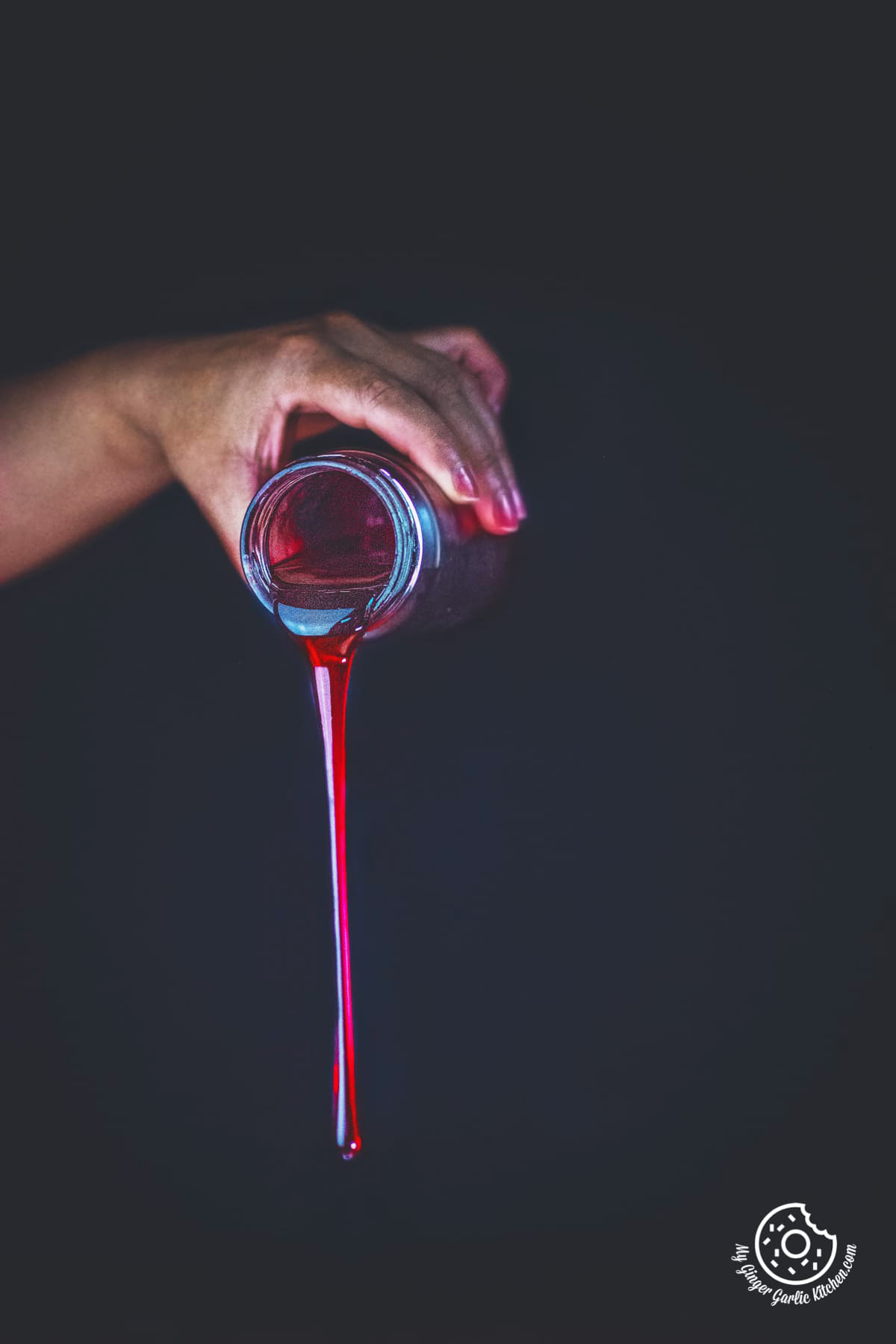 a female pouring rose syrup from the glass bottle