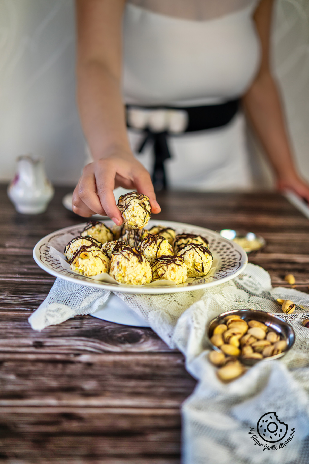 a female hand grabbing cream cheese white chocolate truffles in a white plate