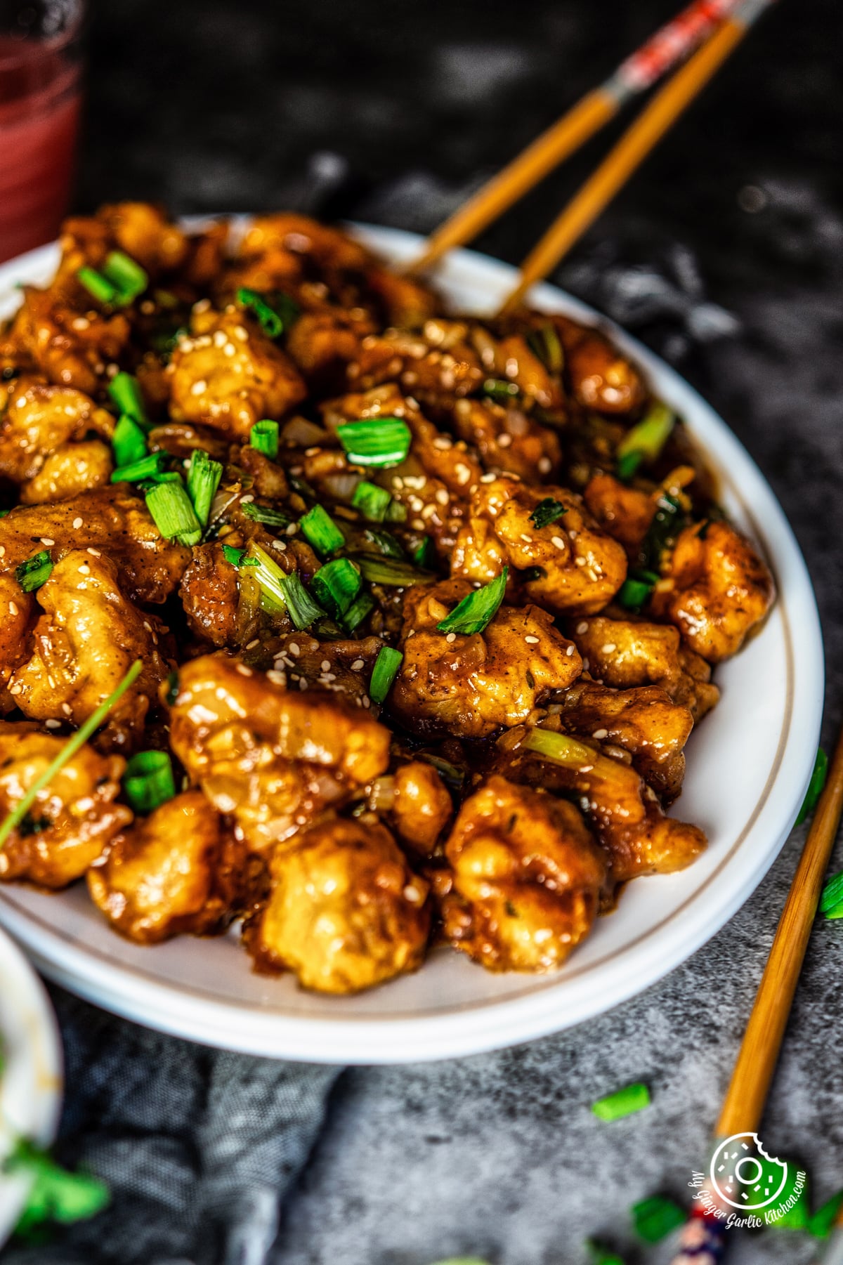 a closeup shot gobi manchurian topped with spring onions served in a white oval plate