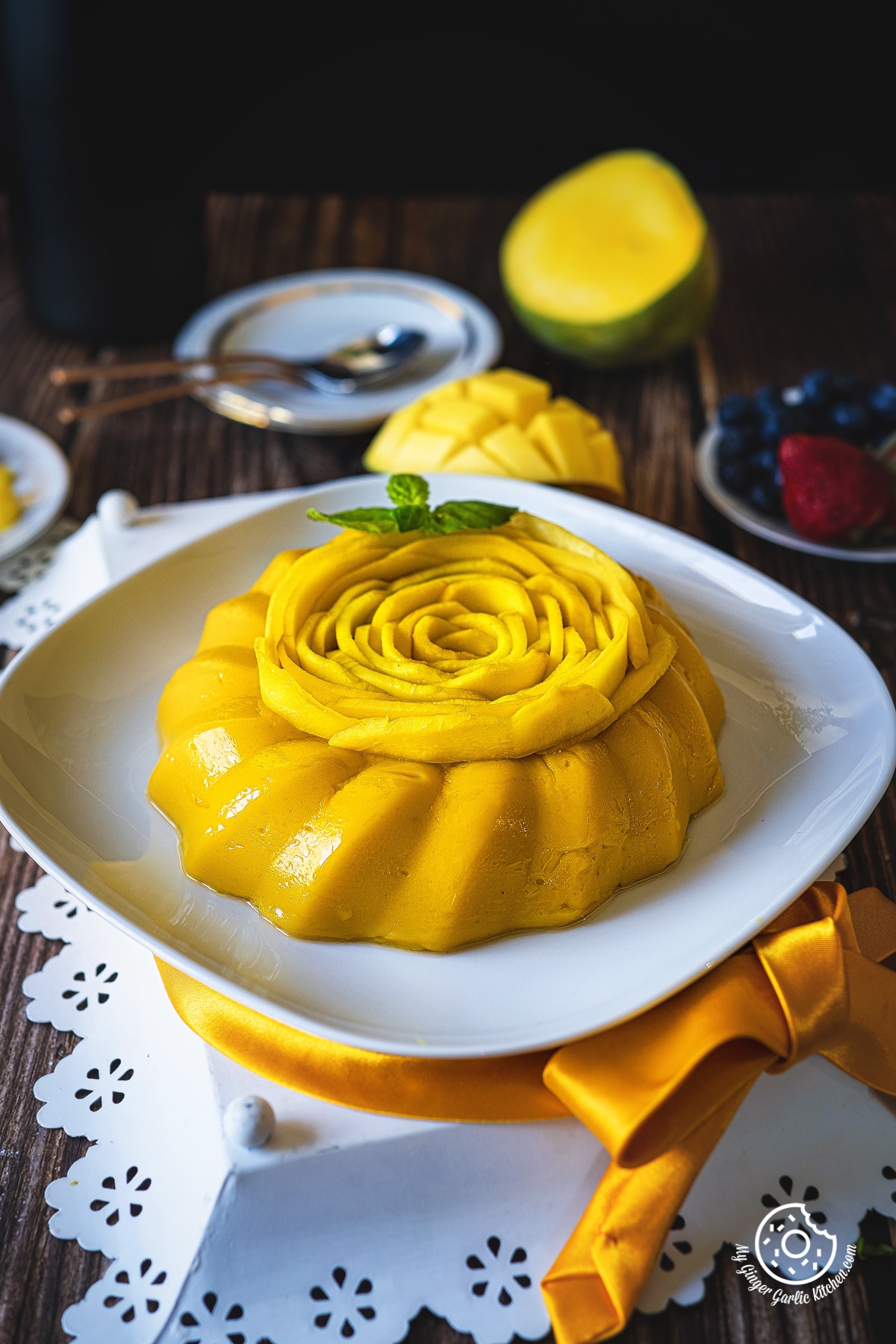 mango pudding decorated with mango rose and sprig of mint kept in a white plate