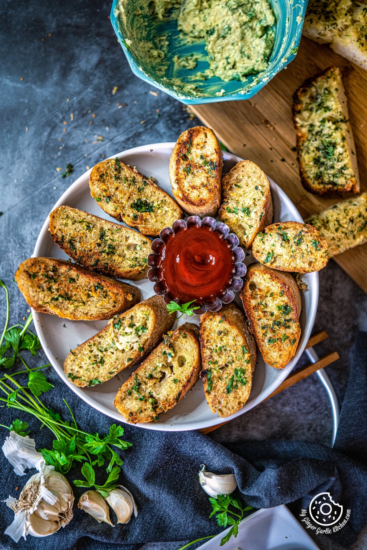 overhead shot of garlic bread in a white plate along with tomato ketchup and cilantro on the side