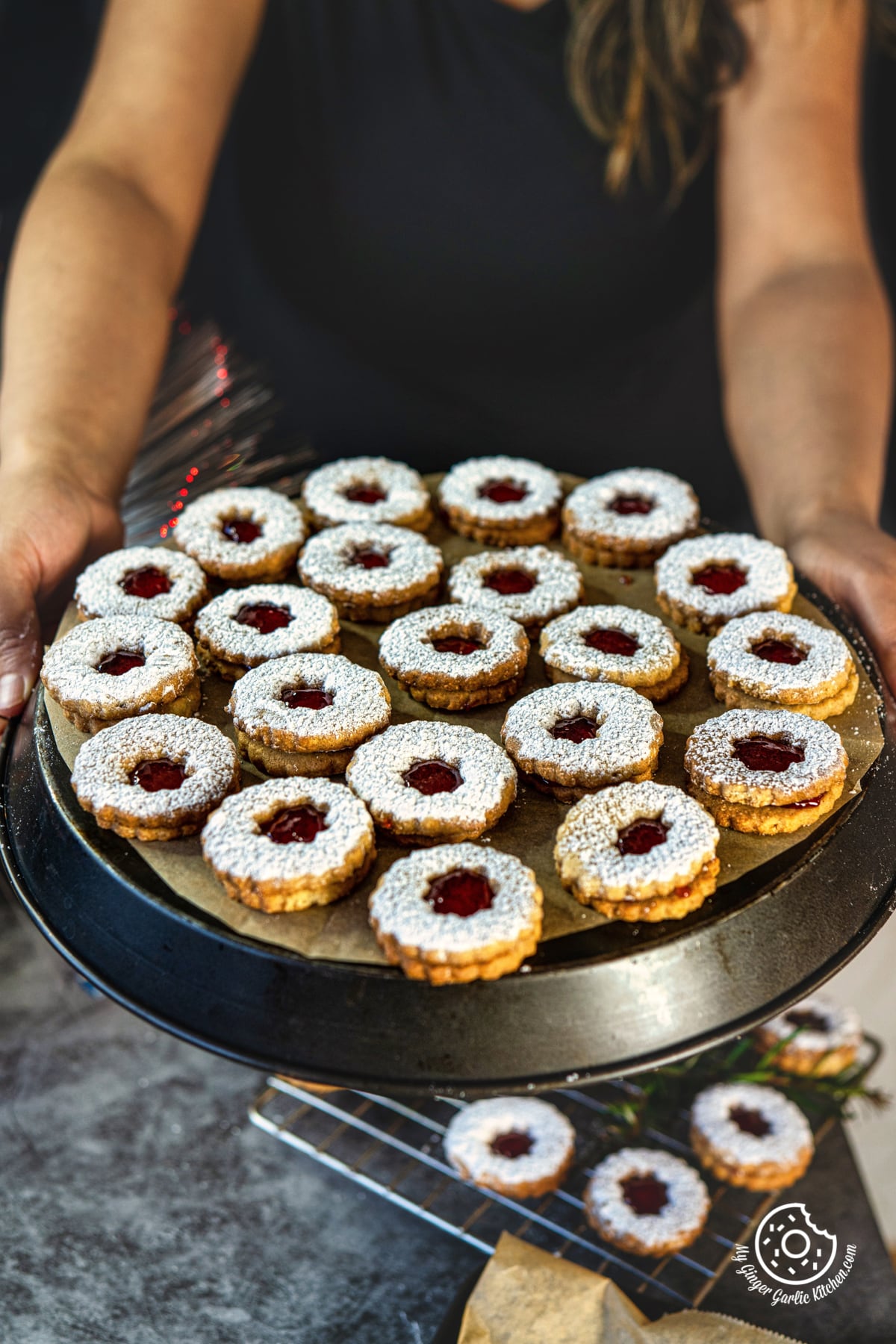 a female holding raspberry linzer cookies tray