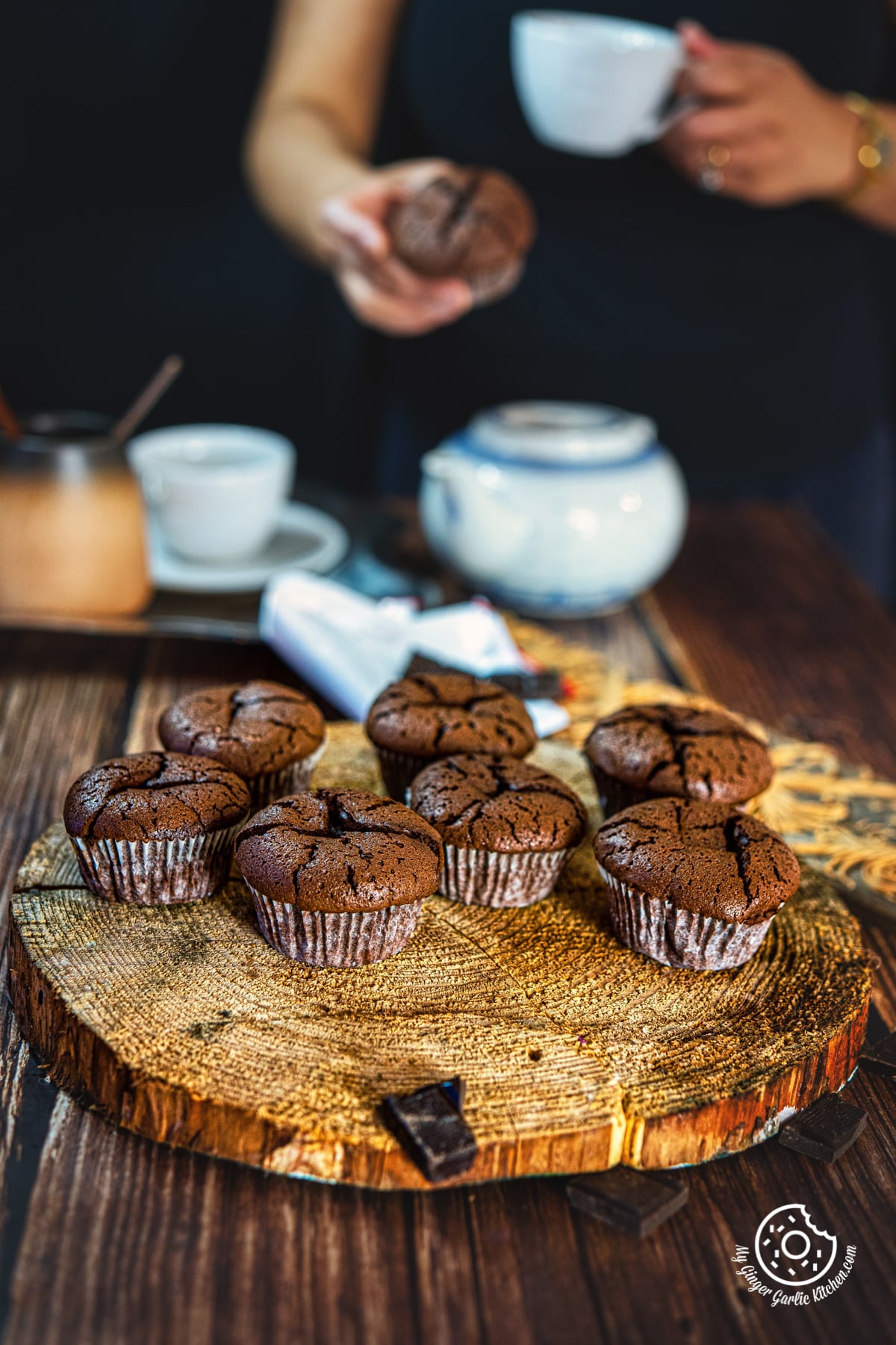 seven pieces of 2 ingredient chocolate muffins on a natural wooden log and a person holding a muffin in the background