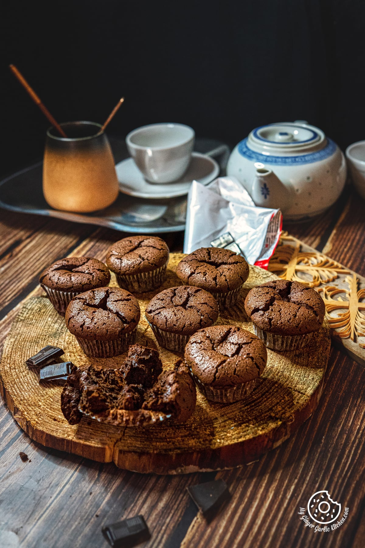 six pieces of 2 ingredient chocolate muffins on a natural wooden log with one torn muffin liner
