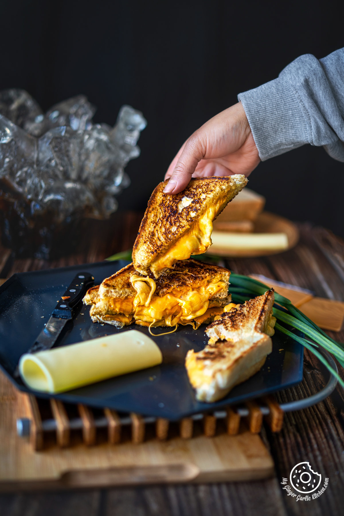 a hand holding a Grilled Cheese Sandwich cut in half showing melting cheesy center