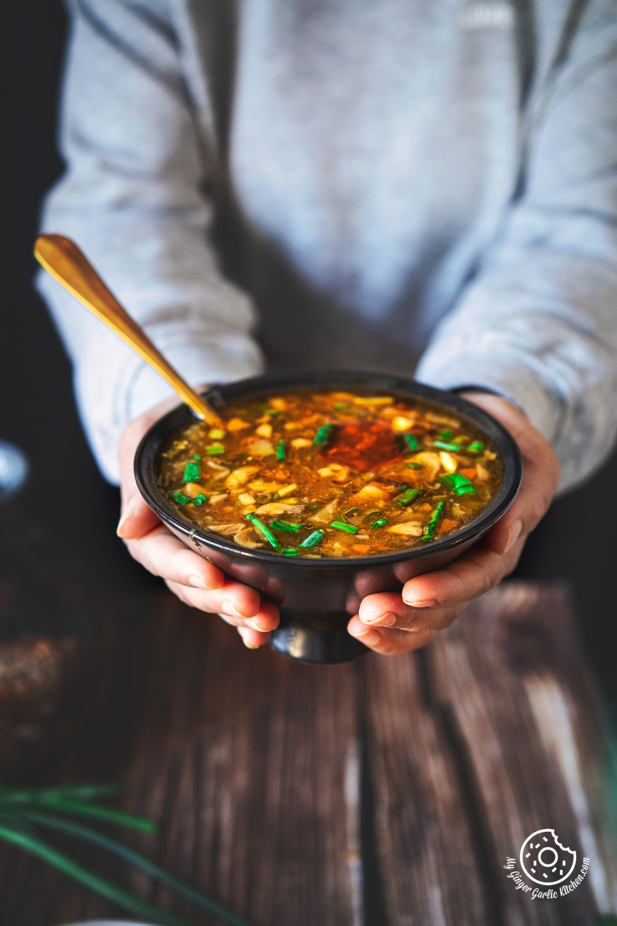 a female holding a black ceramic hot and sour soup bowl