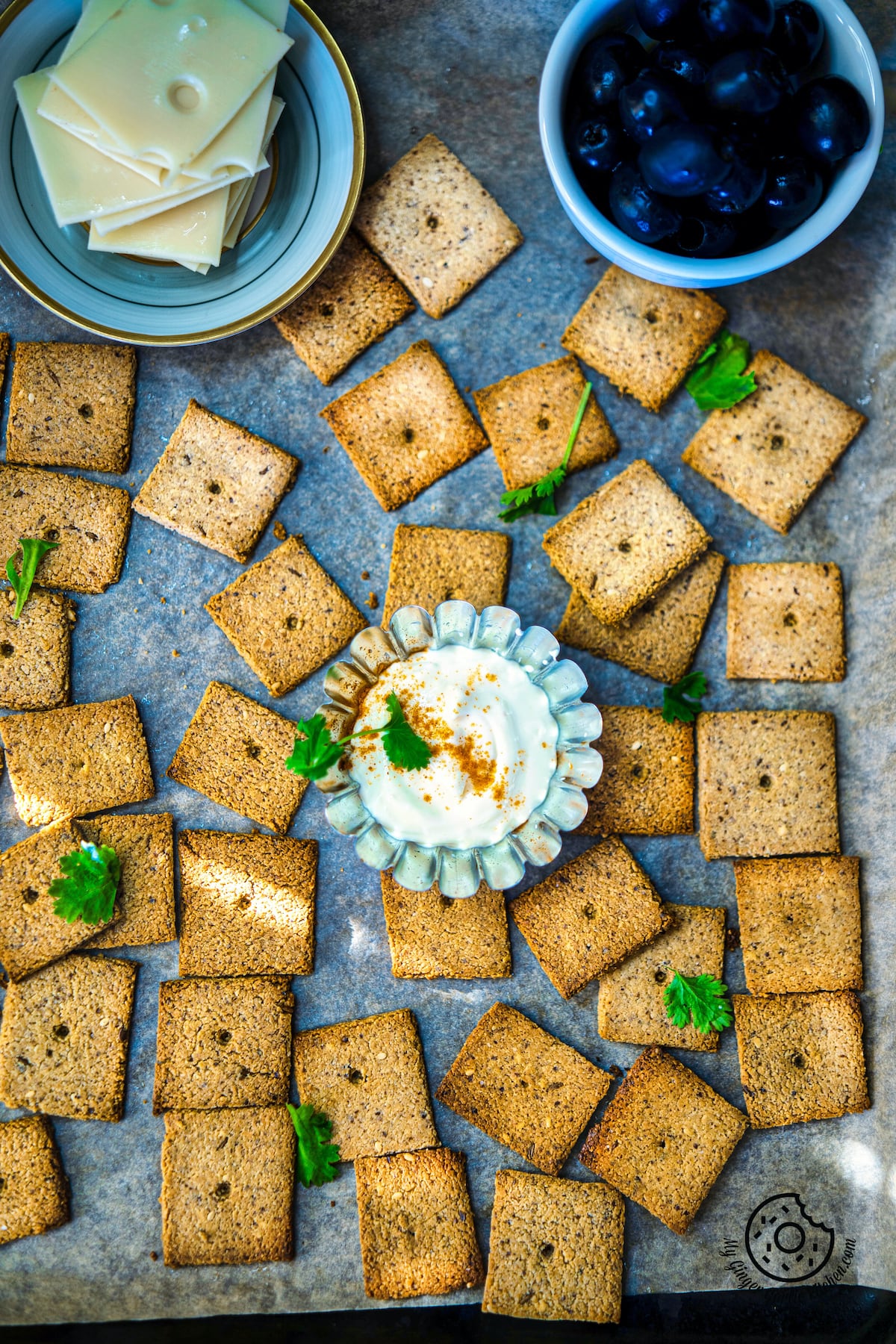 top down view of freshly made almond flour crackers with vegan cheese, olives and dip