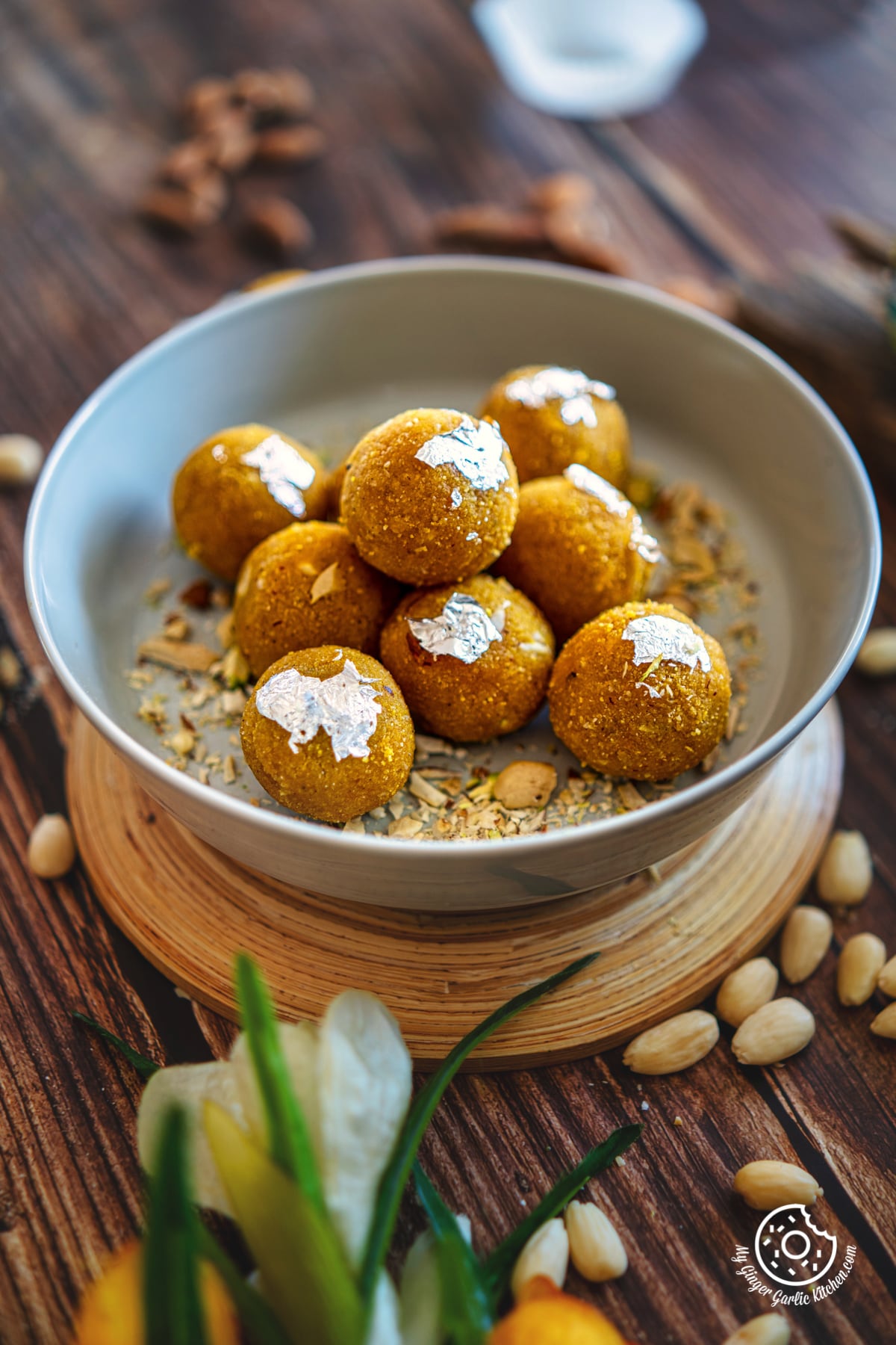 badam ladoo placed on a grey plate with with chopped nuts and almonds on the side