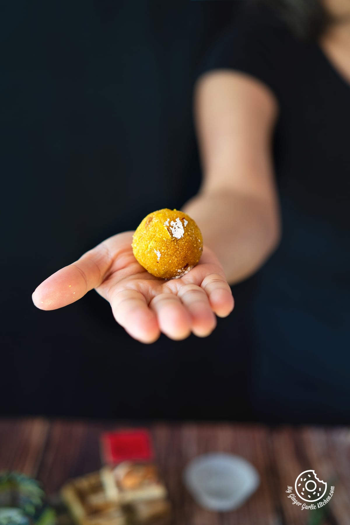 a hand holding one badam ladoo in one hand