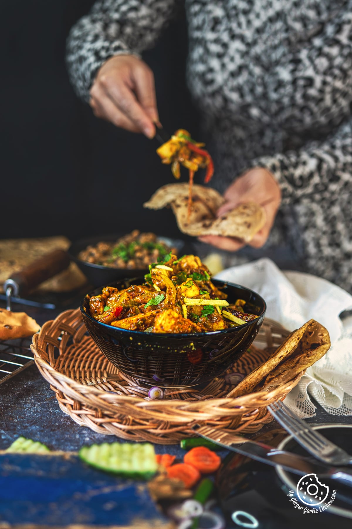paneer khurchan in a black ceramic bowl and a female in the background