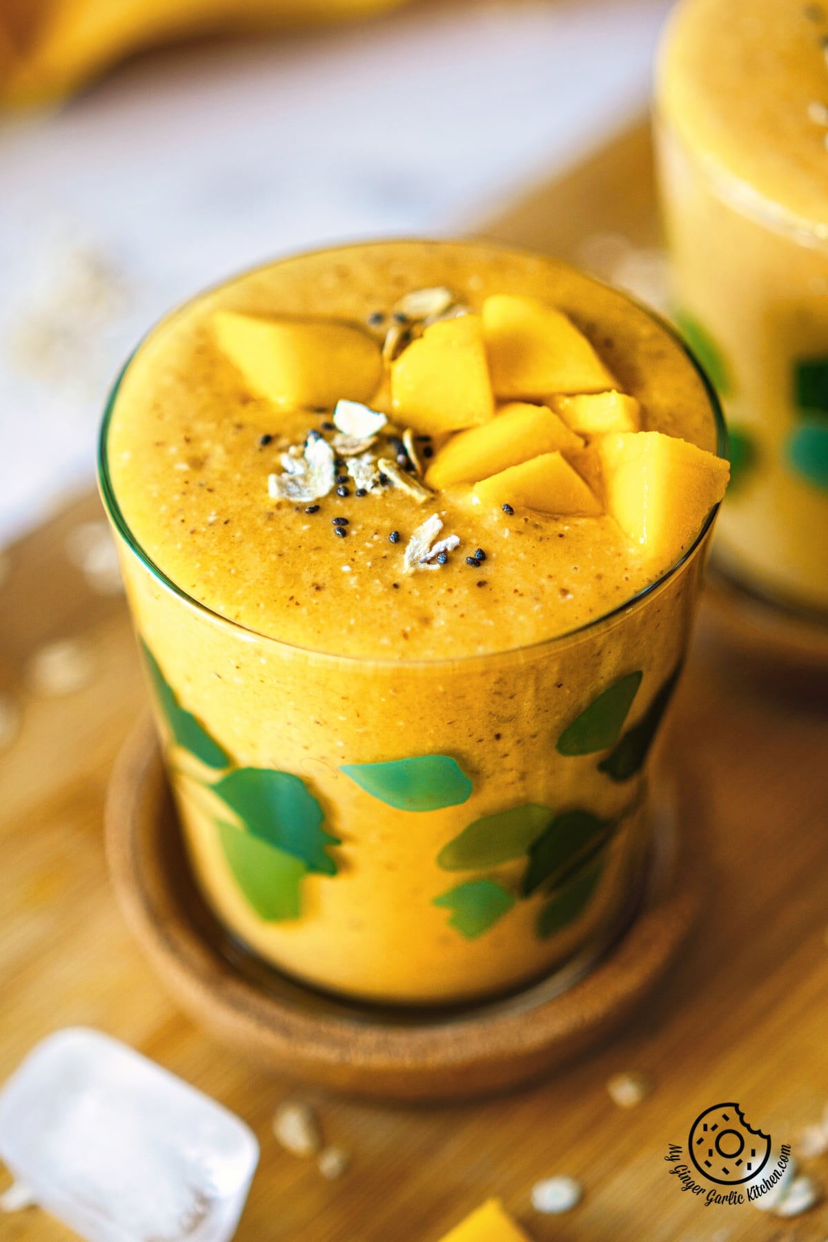 close up shot of mango oats smoothie topped with mango chunks and oats