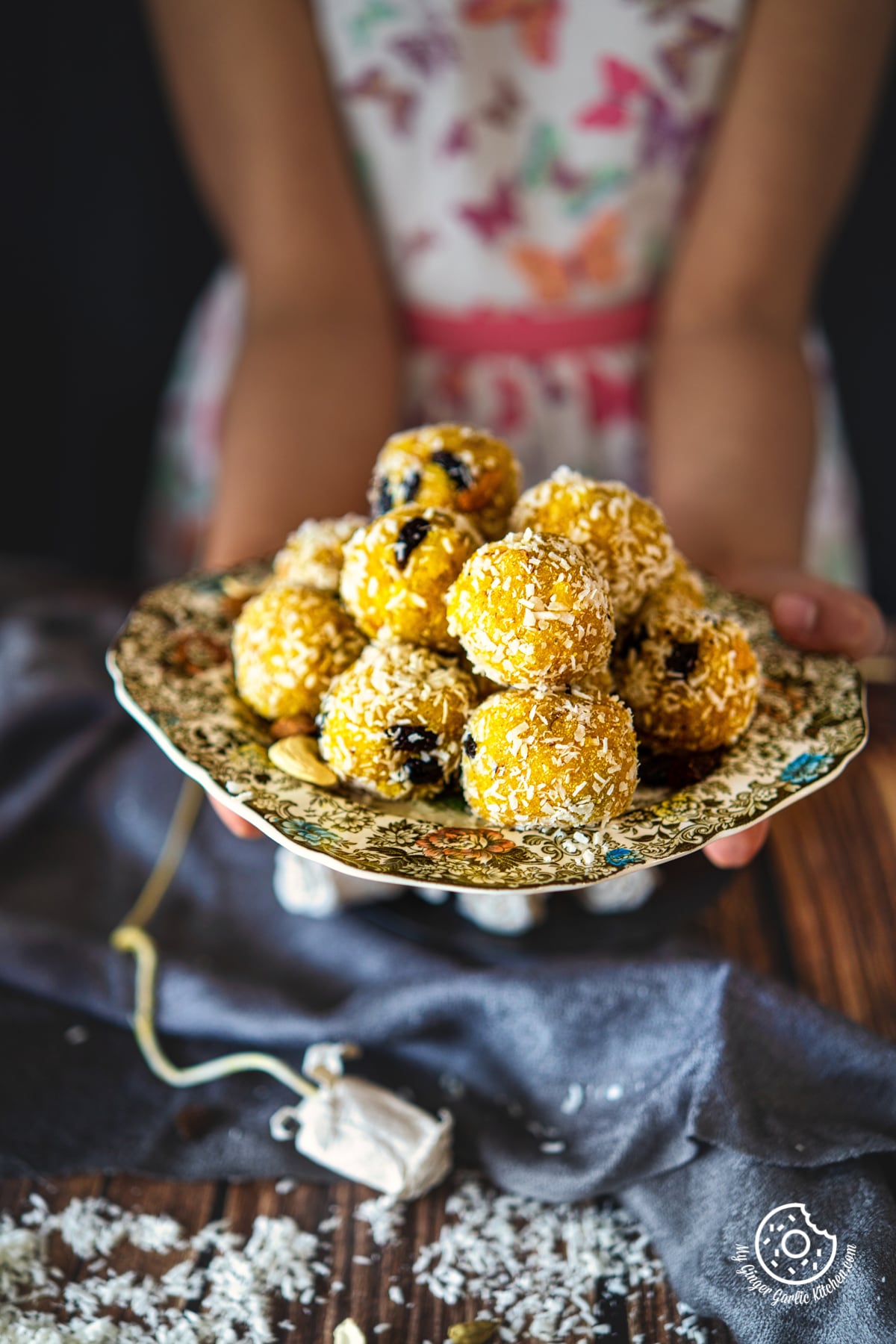 a kid holding a plate full of pineapple ladoos