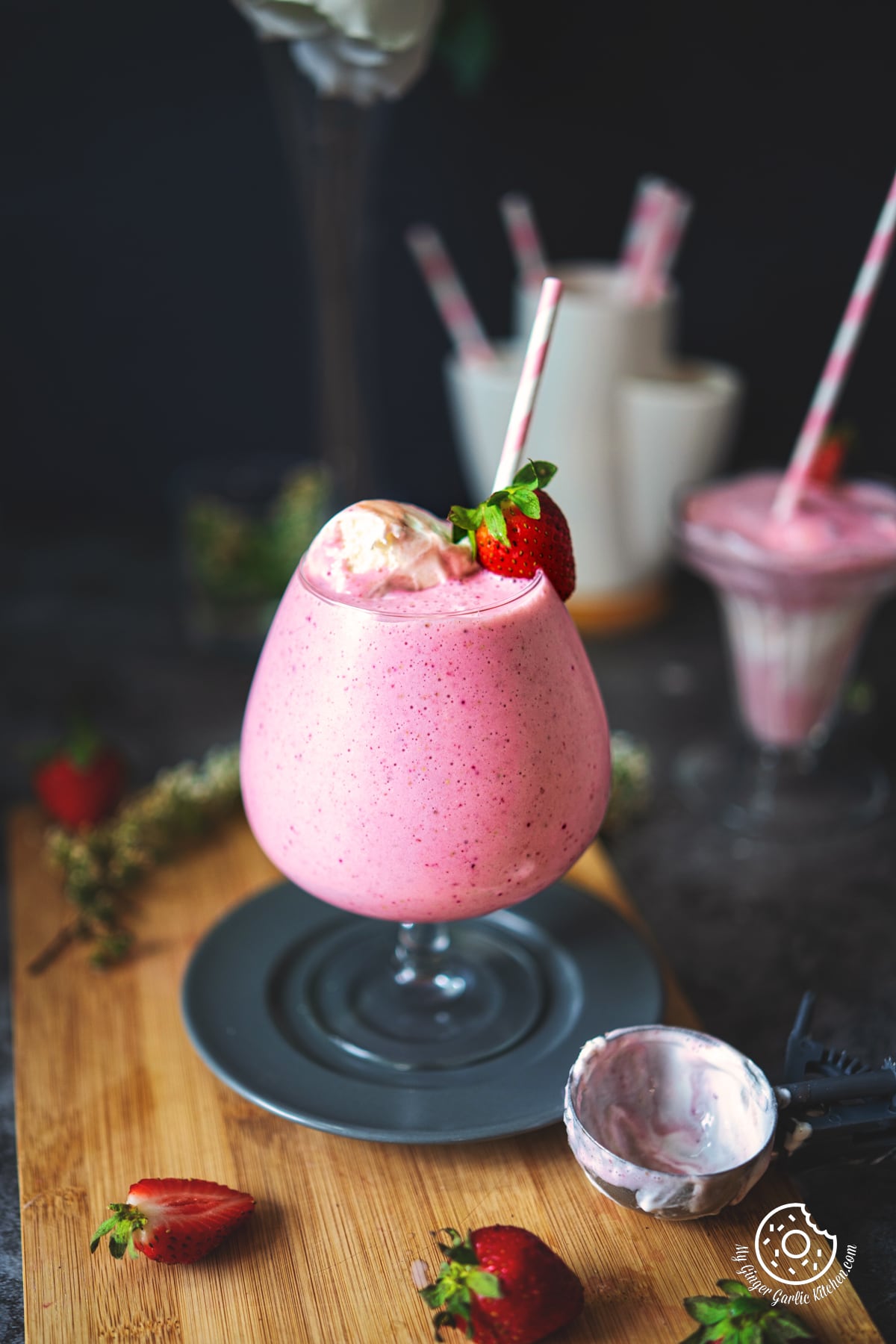 strawberry milkshake in a large glass topped with strawberry ice cream and fresh strawberry