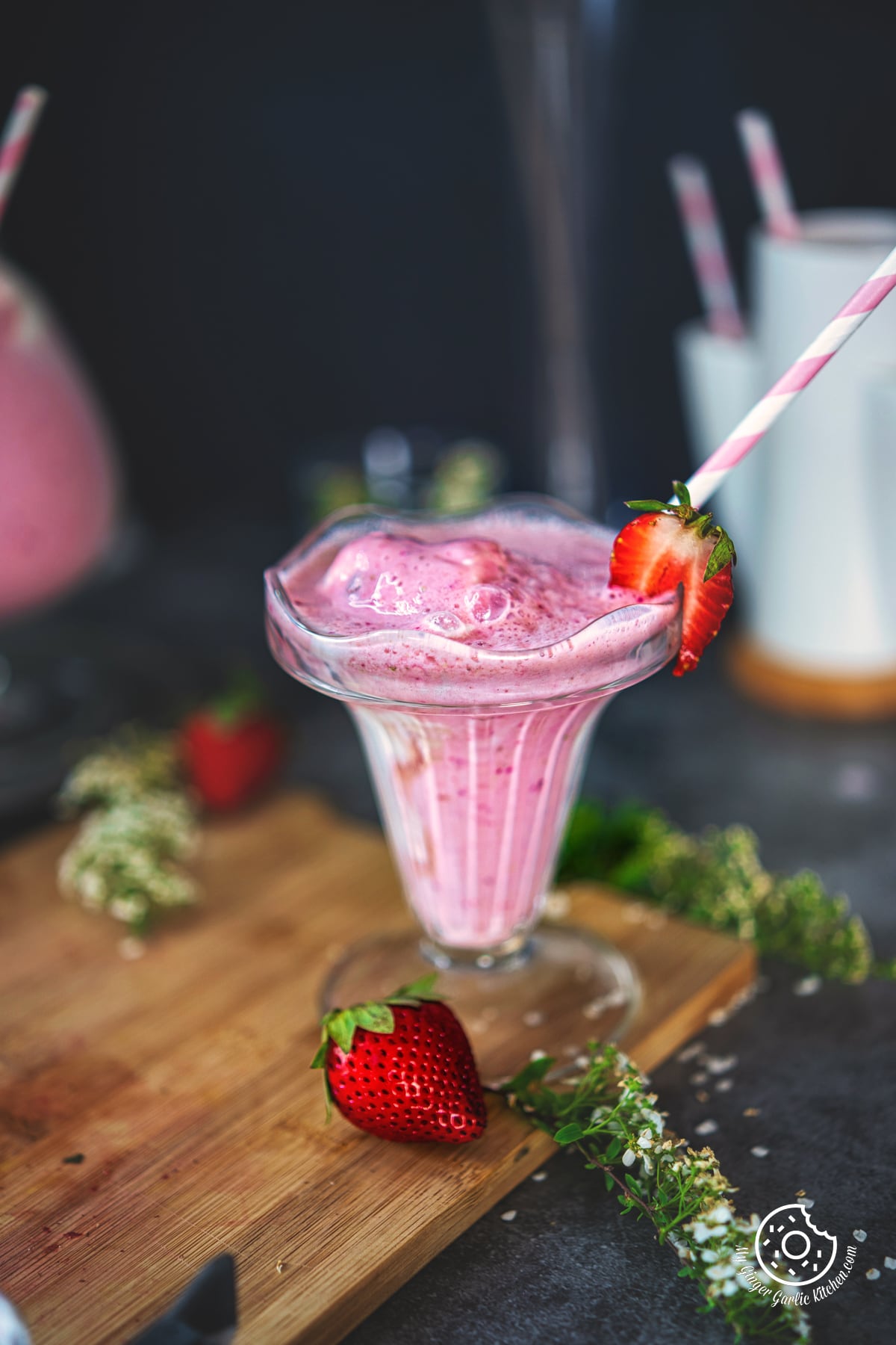 strawberry milkshake in a glass with straw and strawberry