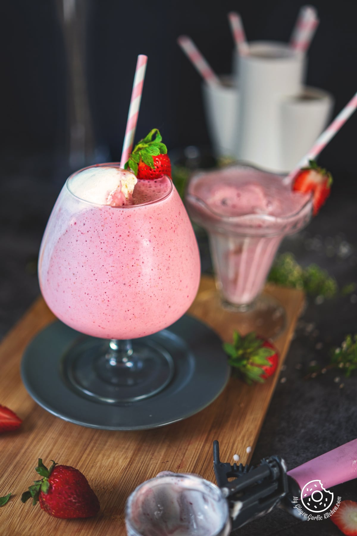 strawberry milkshake with a straw on a grey plate