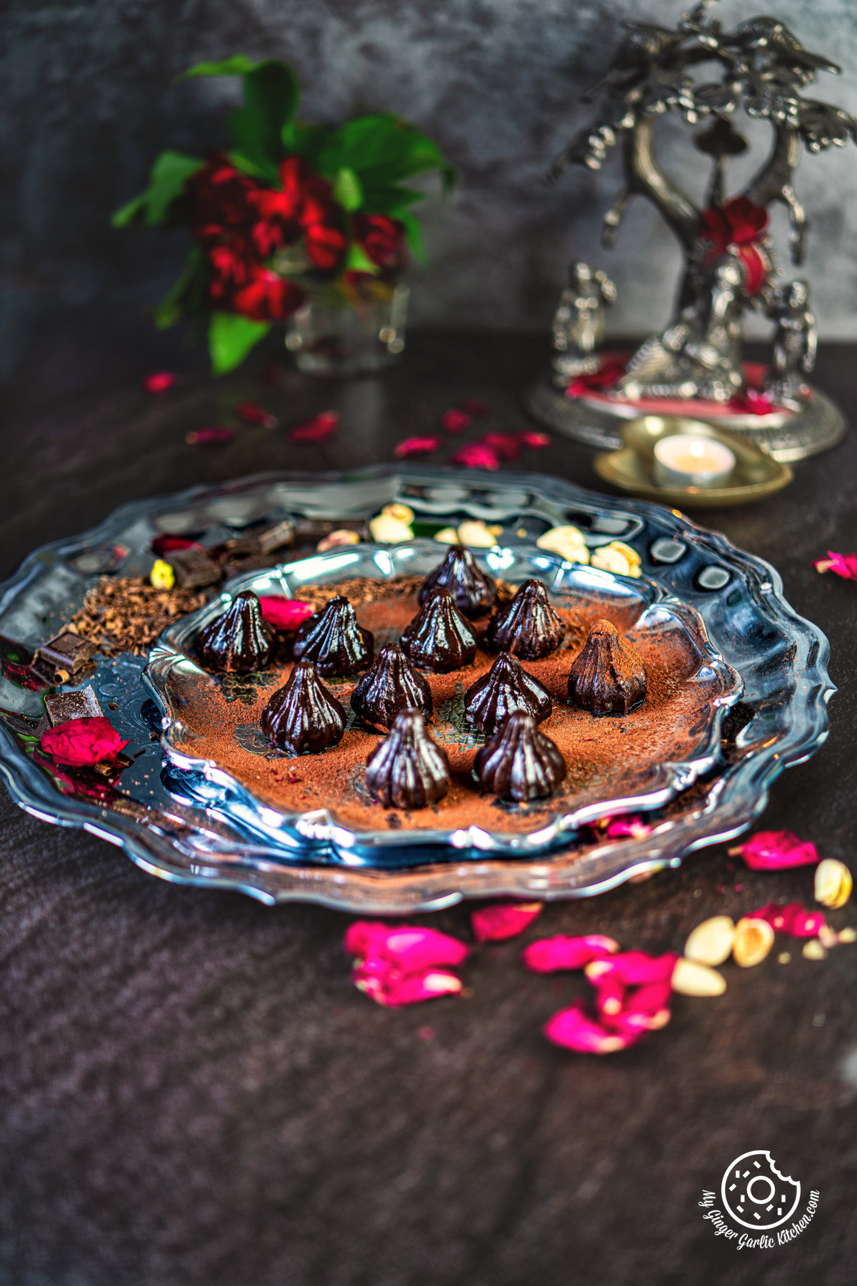 chocolate modak placed on a steel plate garnished with dried rose petals