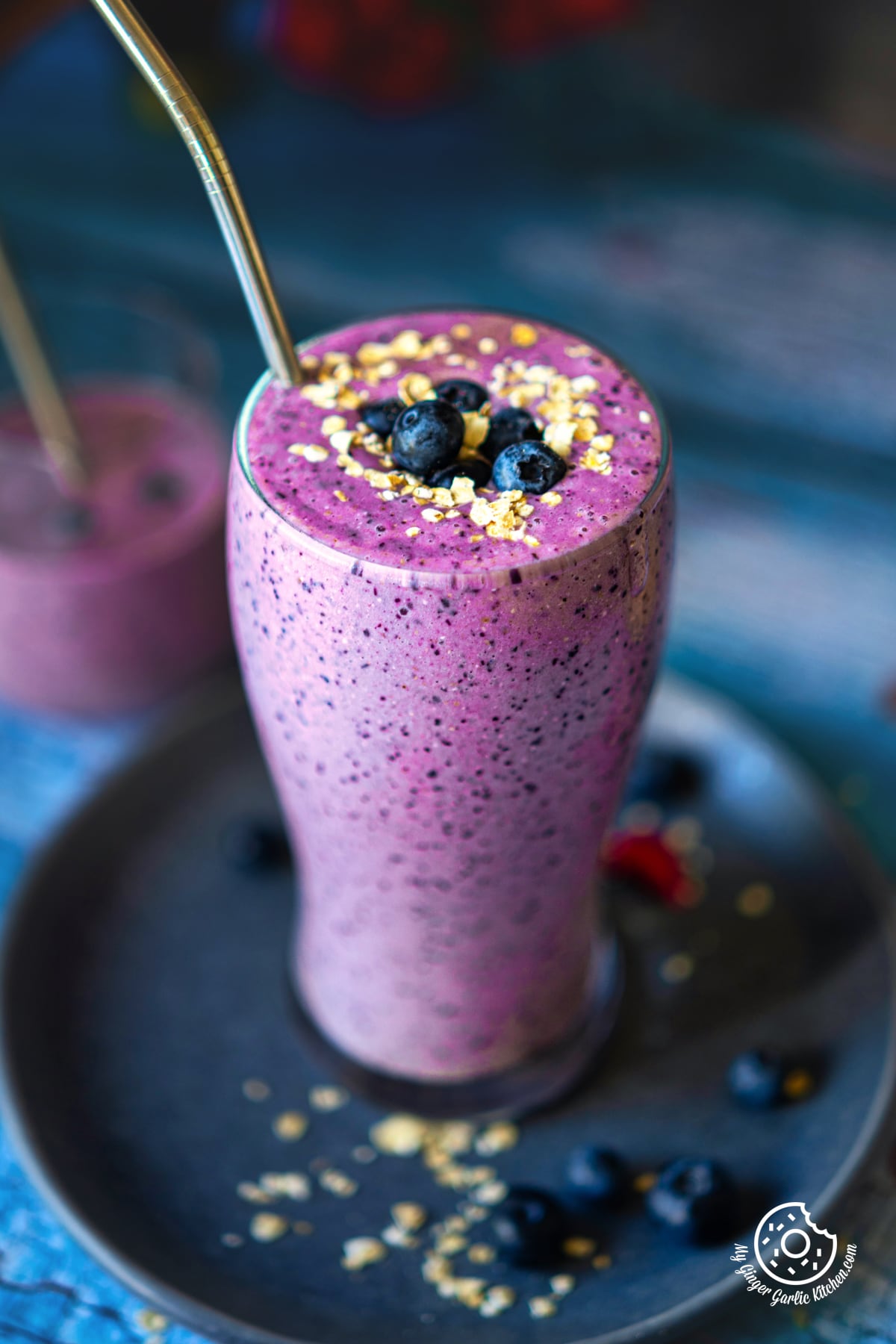 closeup shot of healthy blueberry pie smoothie glass topped with blueberries and oats. #blueberrypiesmoothie