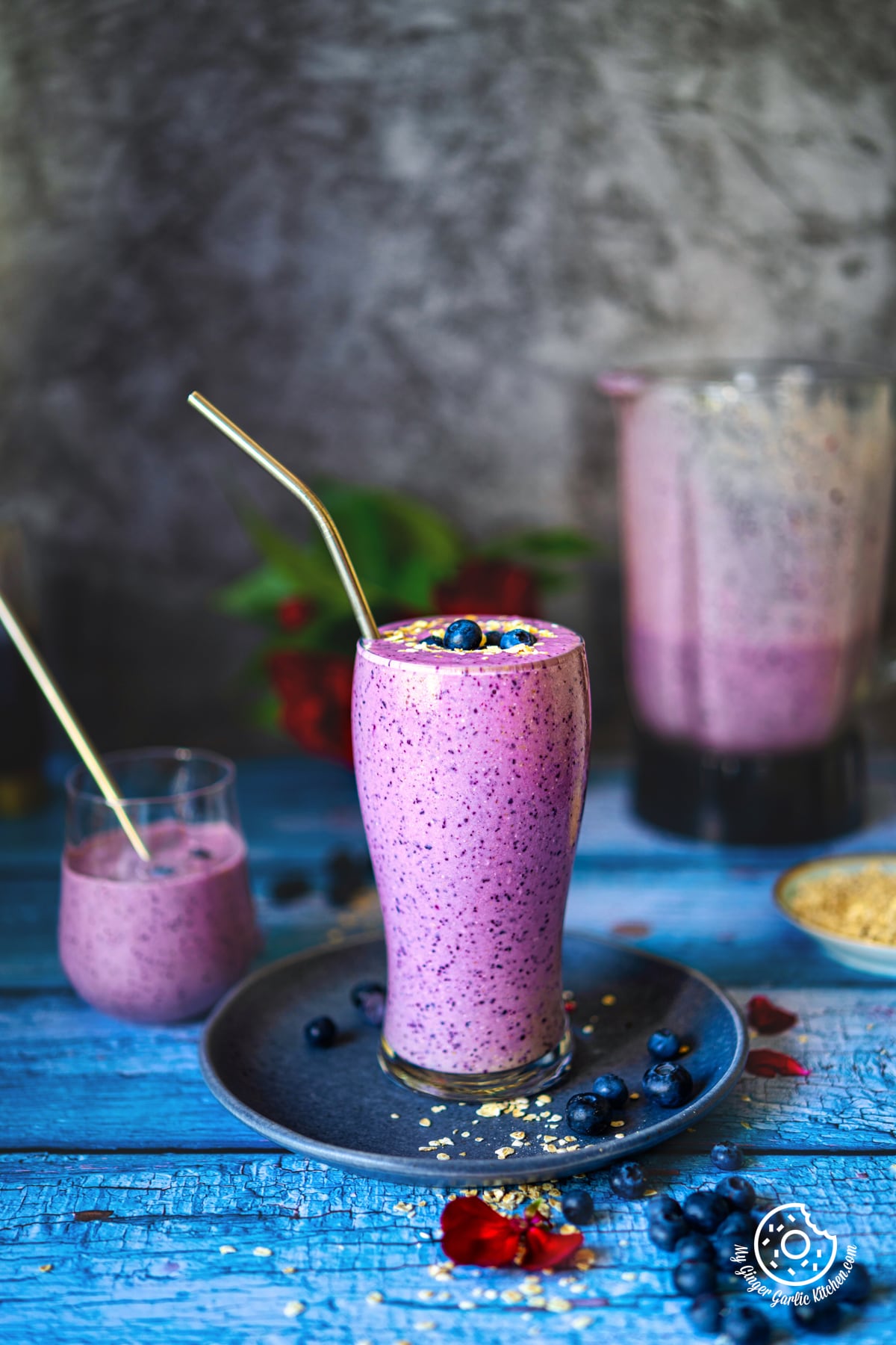 healthy breakfast blueberry pie smoothie glass topped with blueberries and oats with a glass in the background