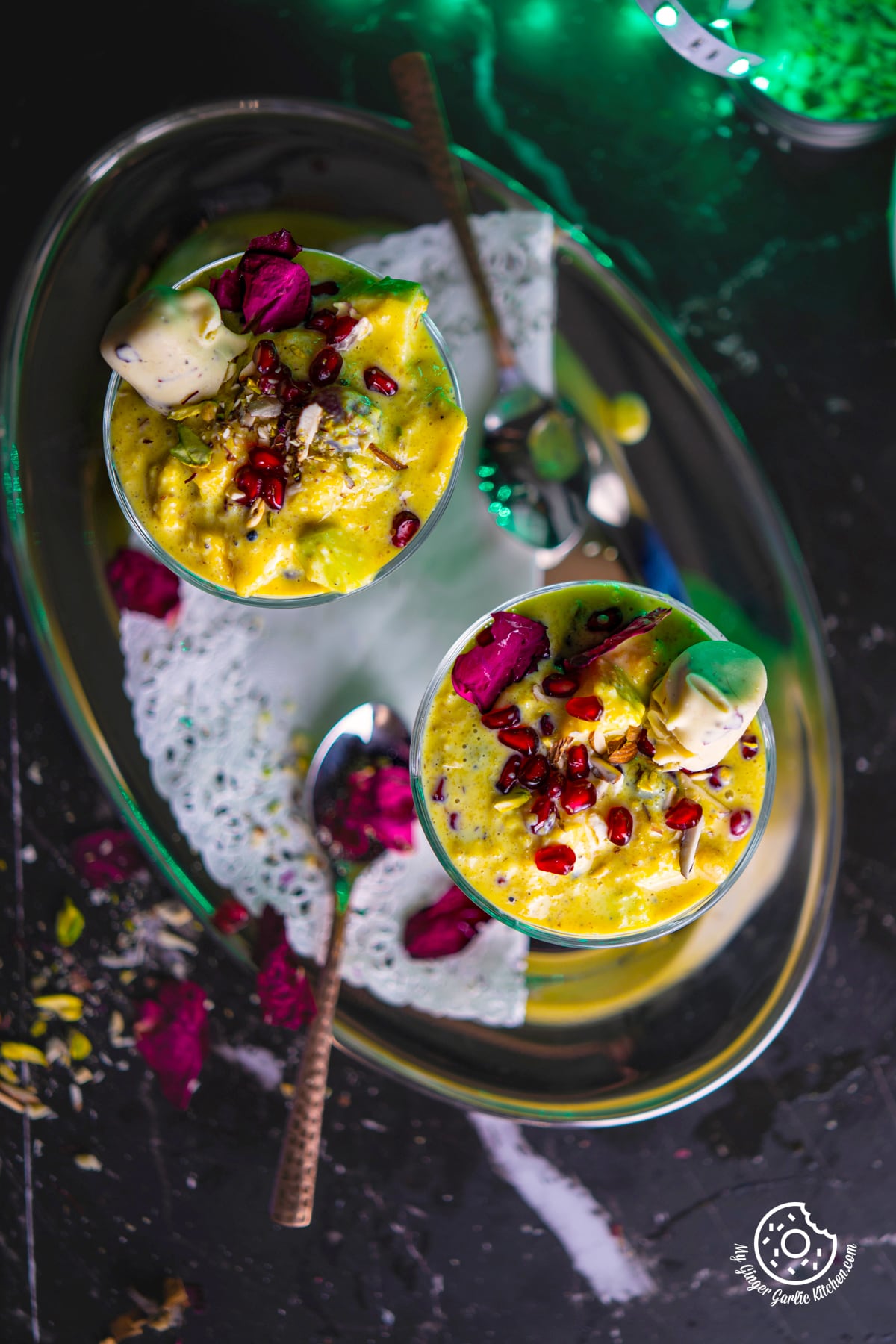 overhead shot of two fruit rabri glasses with rose petals on the side