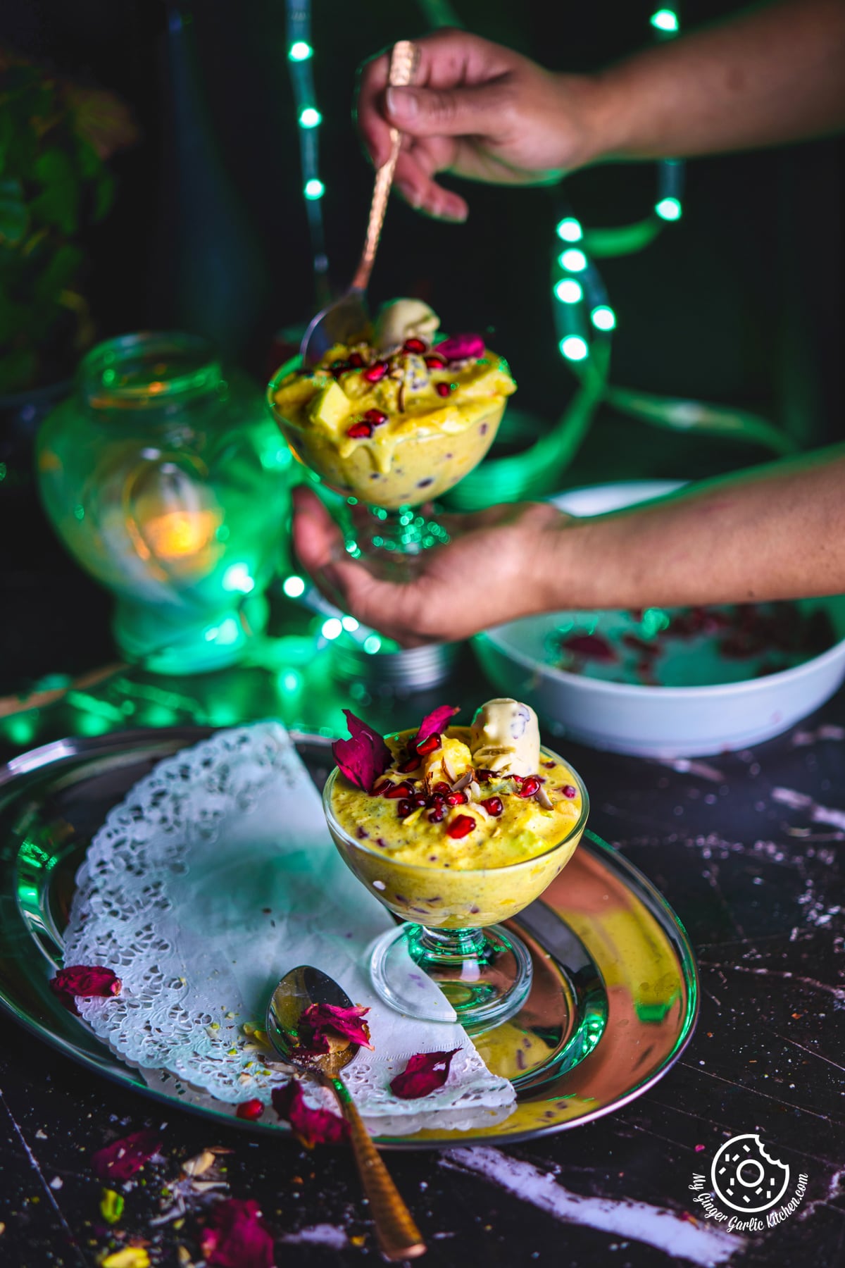 fruit rabri in a transparent dessert glass with a someone holding fruit rabri glass in the background