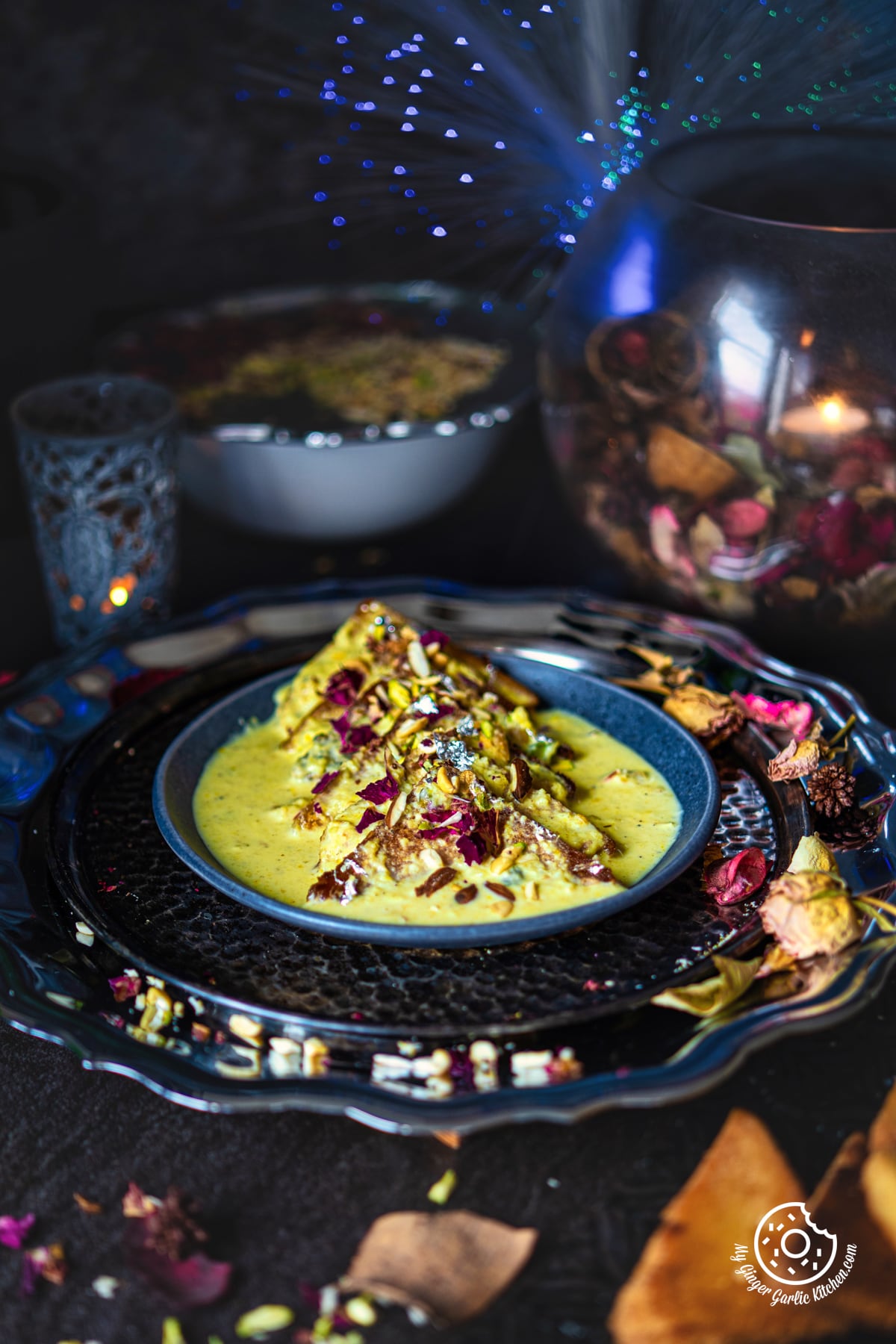 shahi tukda also known as shahi tukra served in a grey ceramic plate with flowers and candle on the side