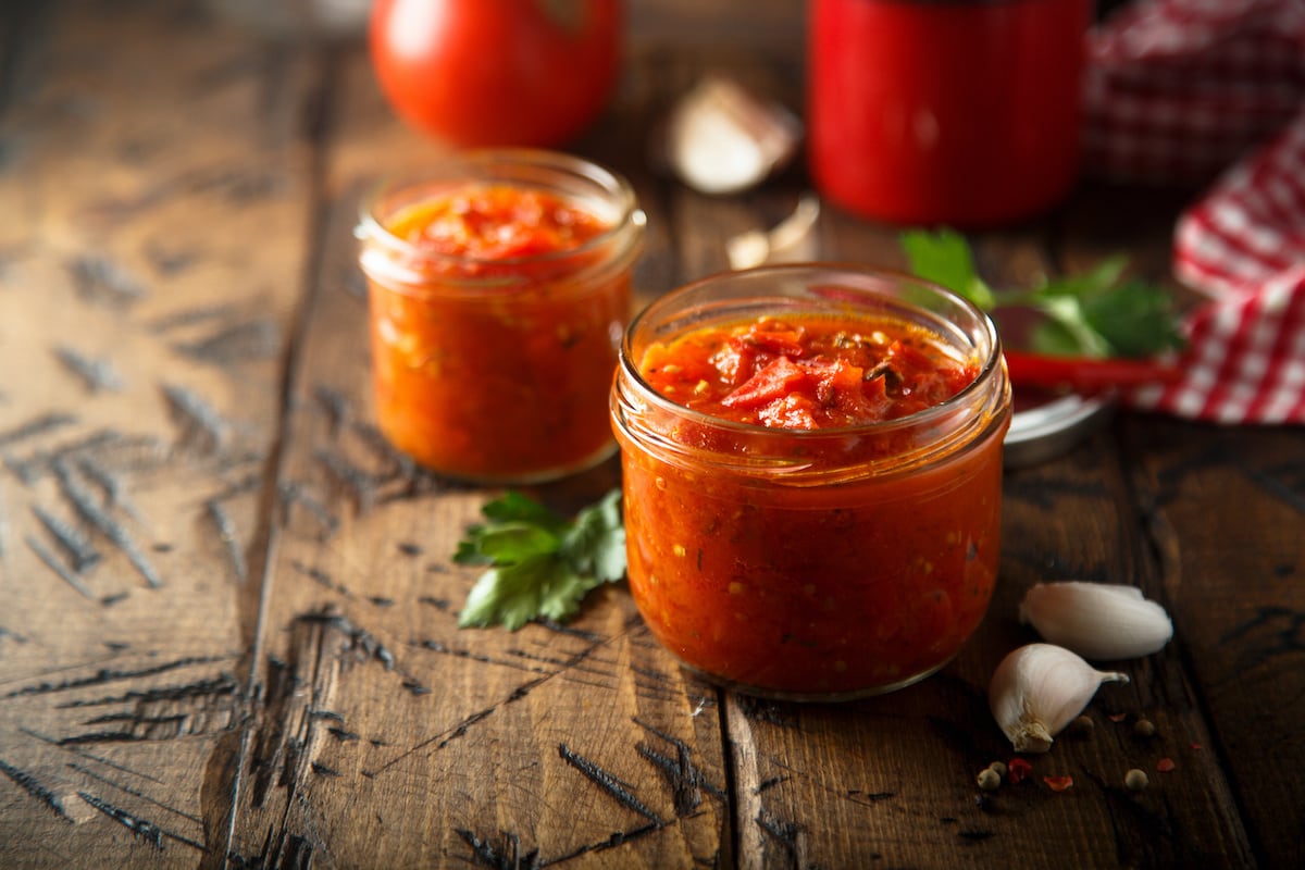 tomato chutney in a transparent jar with one more jar in the background