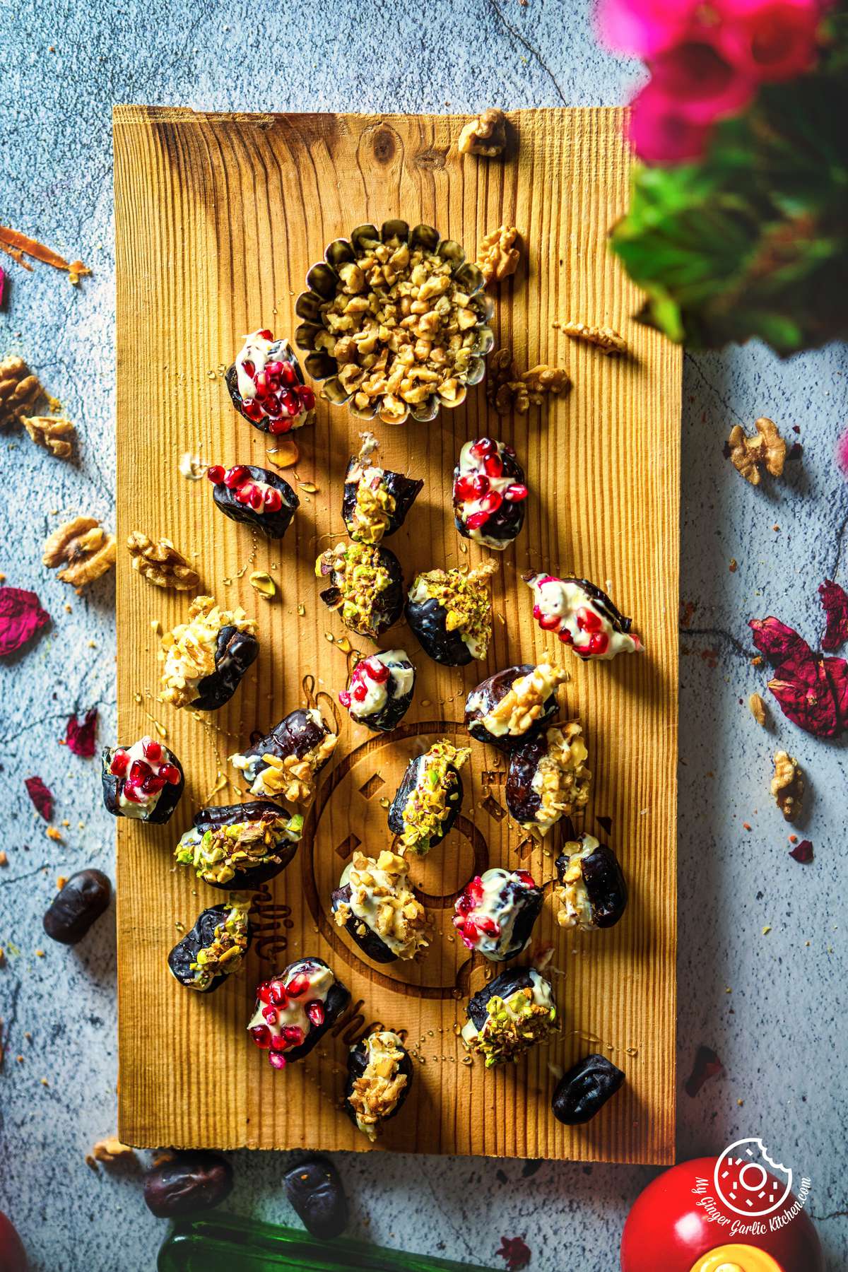 overhead shot of stuffed dates with cream cheese topped with chopped walnuts, chopped pistachios, and pomegranate arils