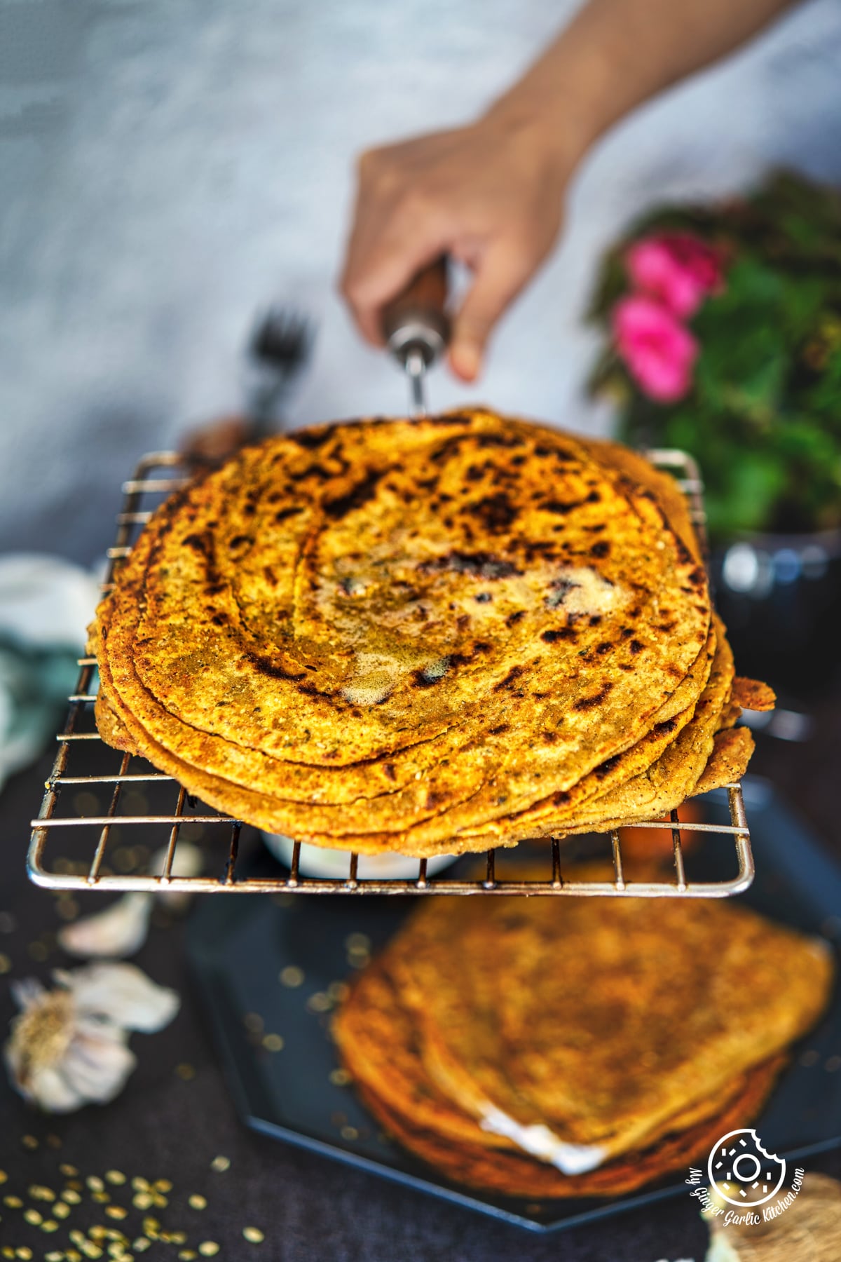 a hand holding a wire rack with khichdi paratha