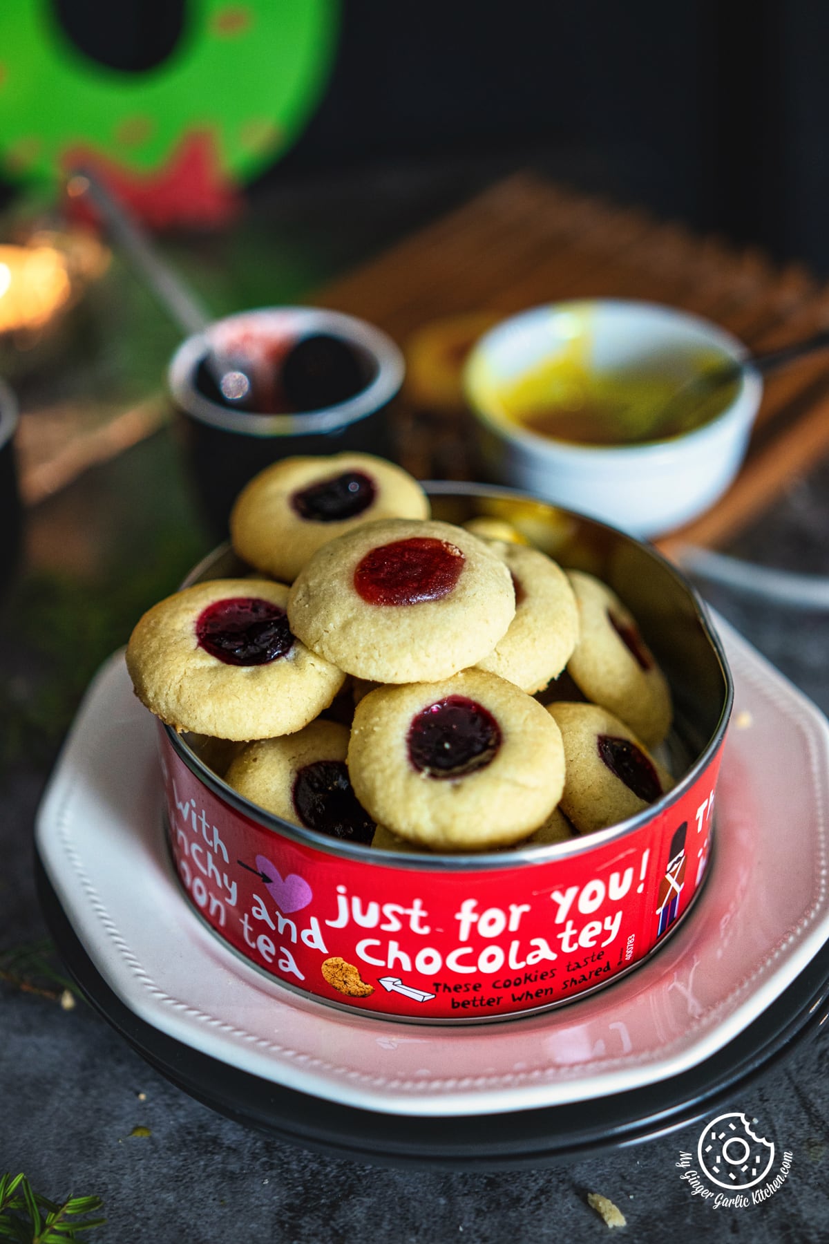 a closeup of red metal cookie box stacked with thumbprint cookies