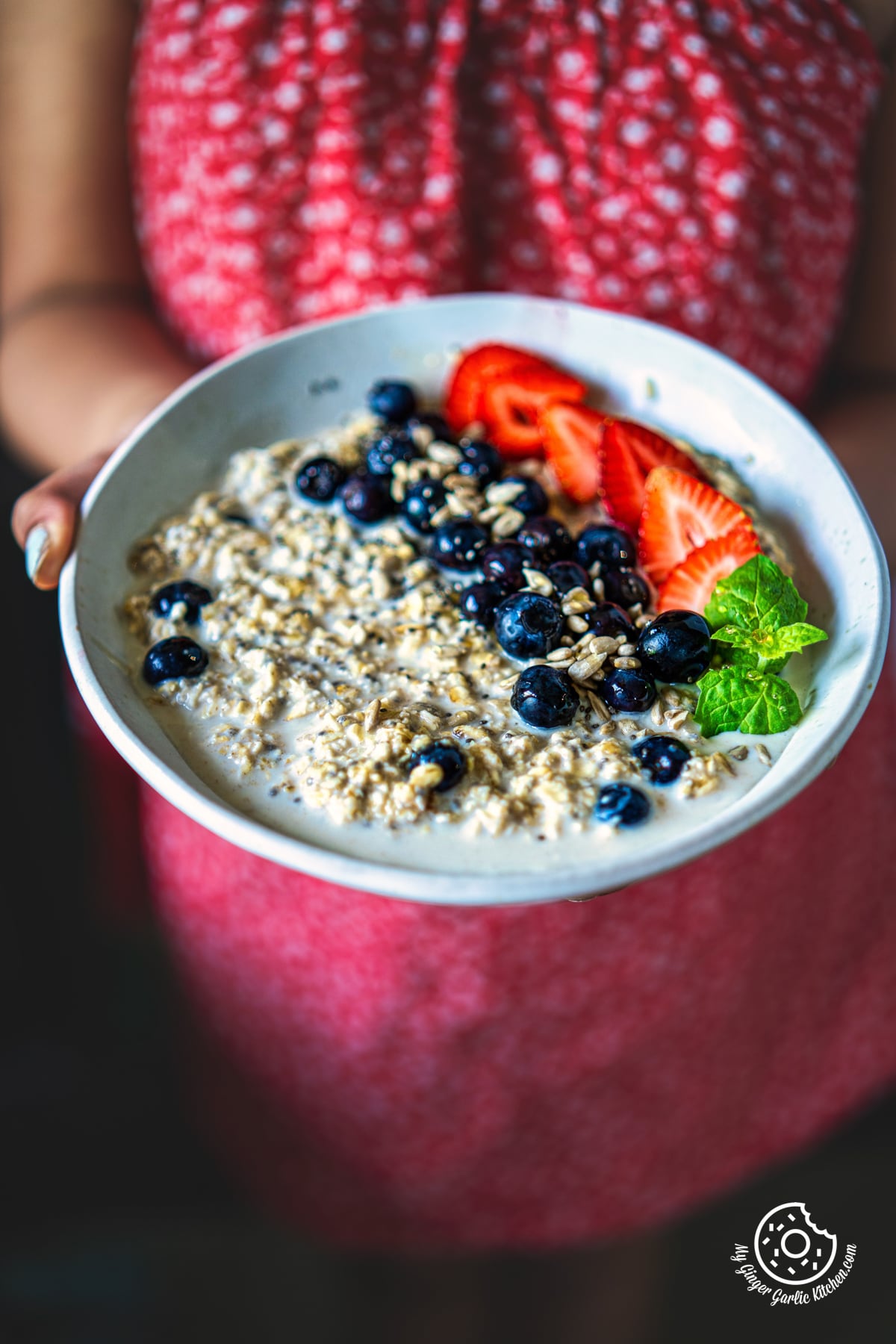 a person holding a blueberry overnight oats bowl