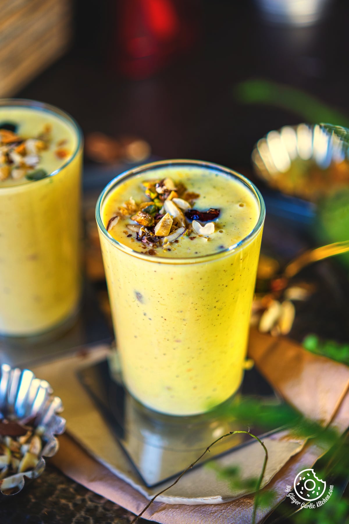 closeup photo of two glasses of badam milkshake with chopped nuts on top