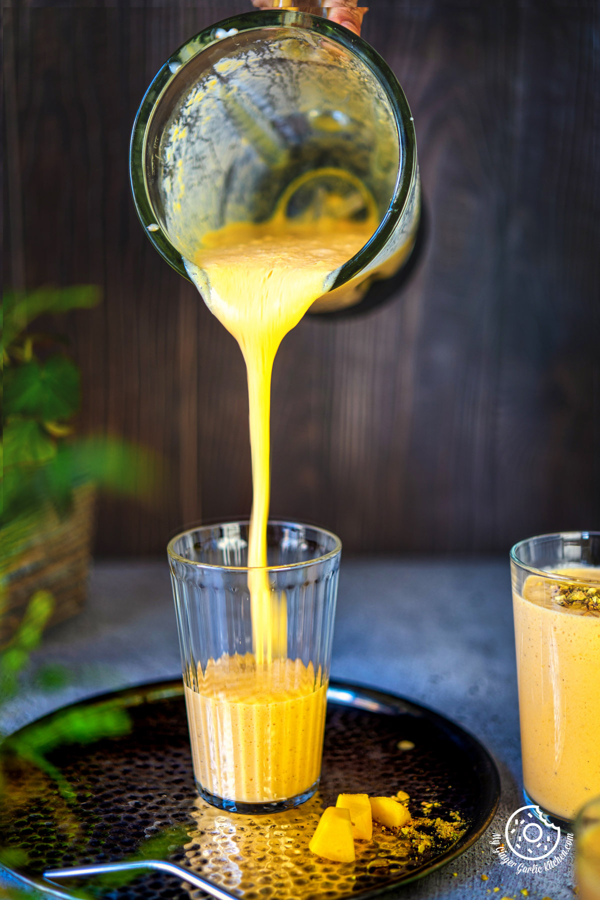 mango lassi being poured into a transparent glass