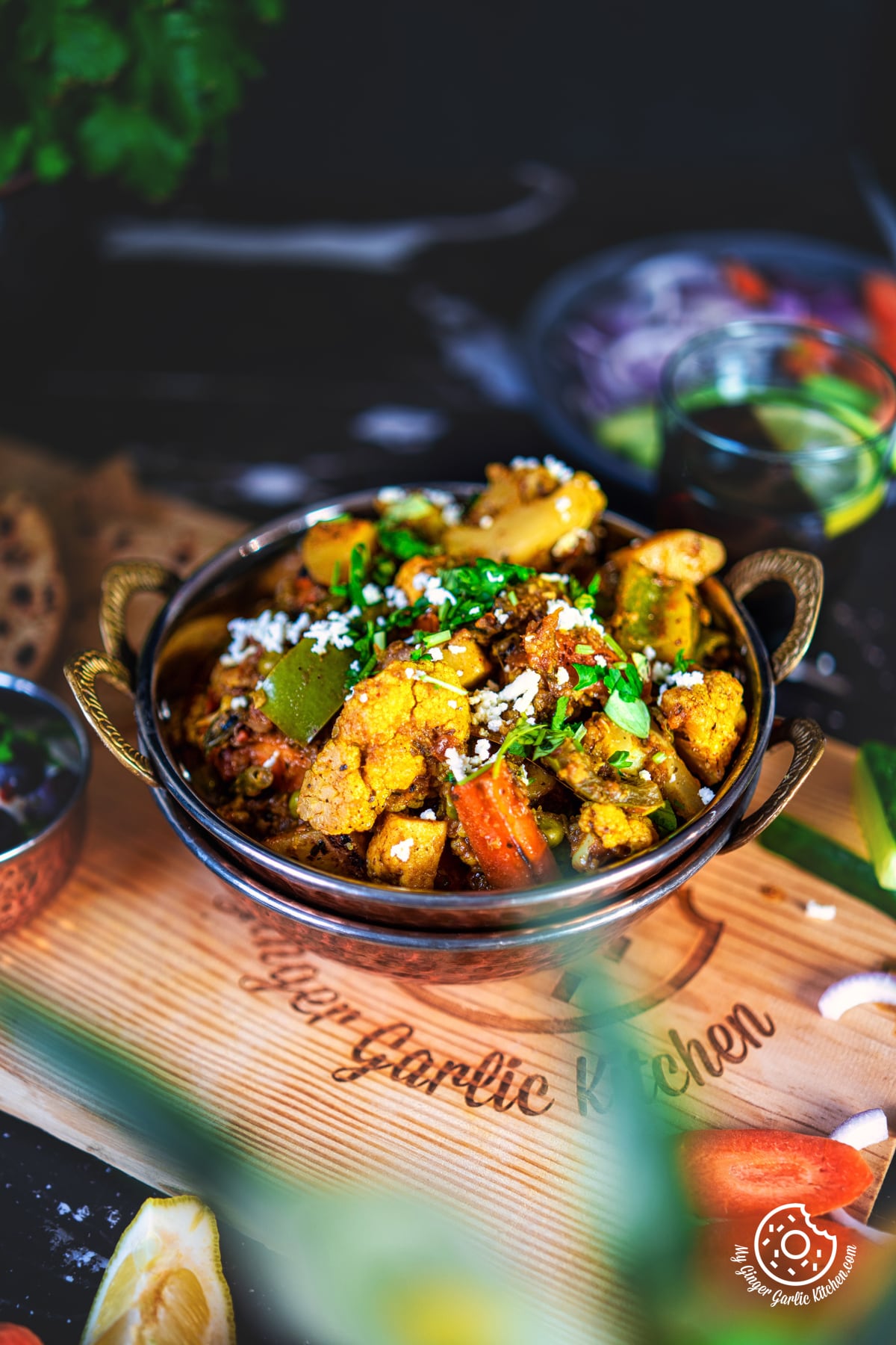 closeup of mixed veg garnished with coriander and grated paneer in a copper kadai