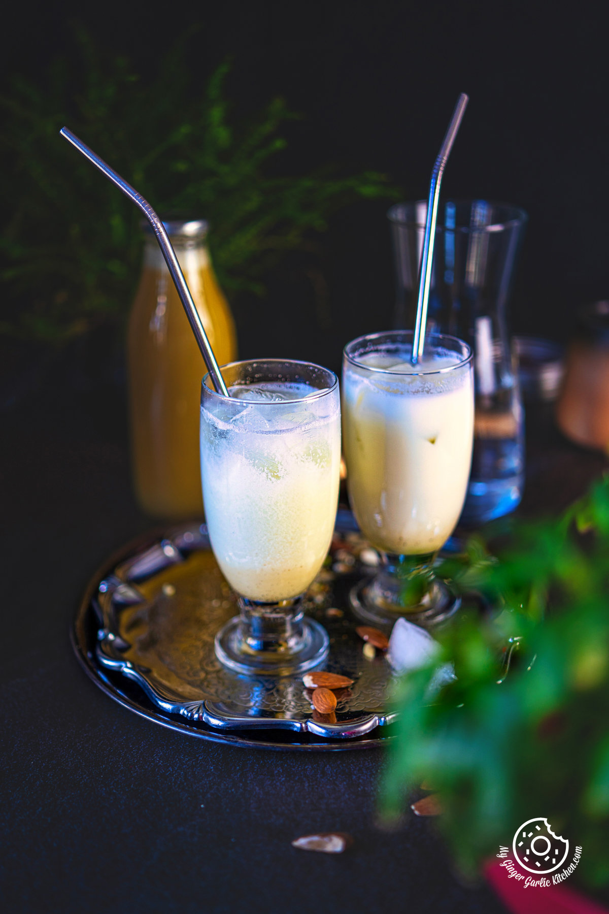 photo of two glasses of a badam sharbat drink with straws on a tray