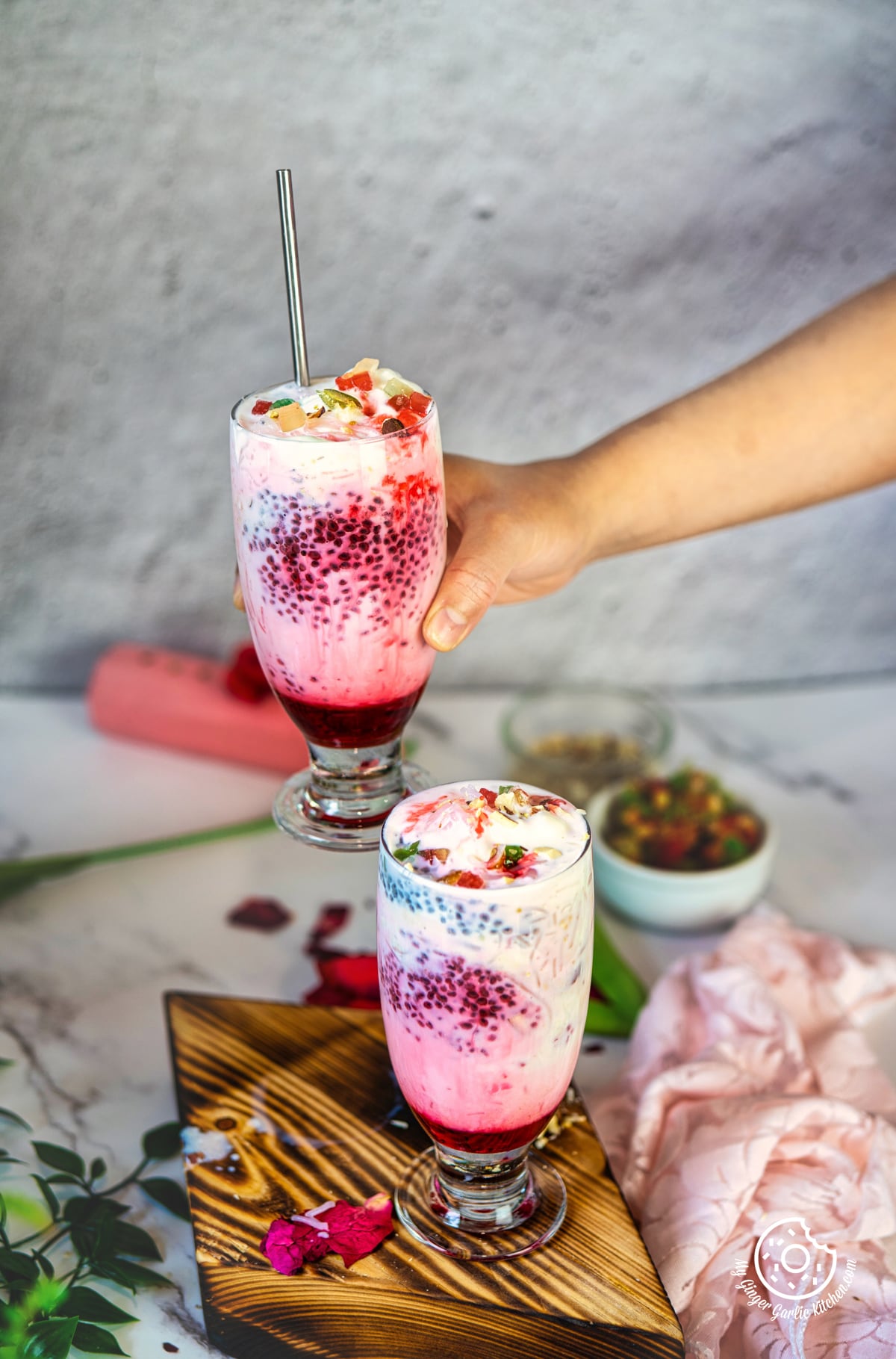 photo of a person holding a glass of fruity pink falooda dessert drink