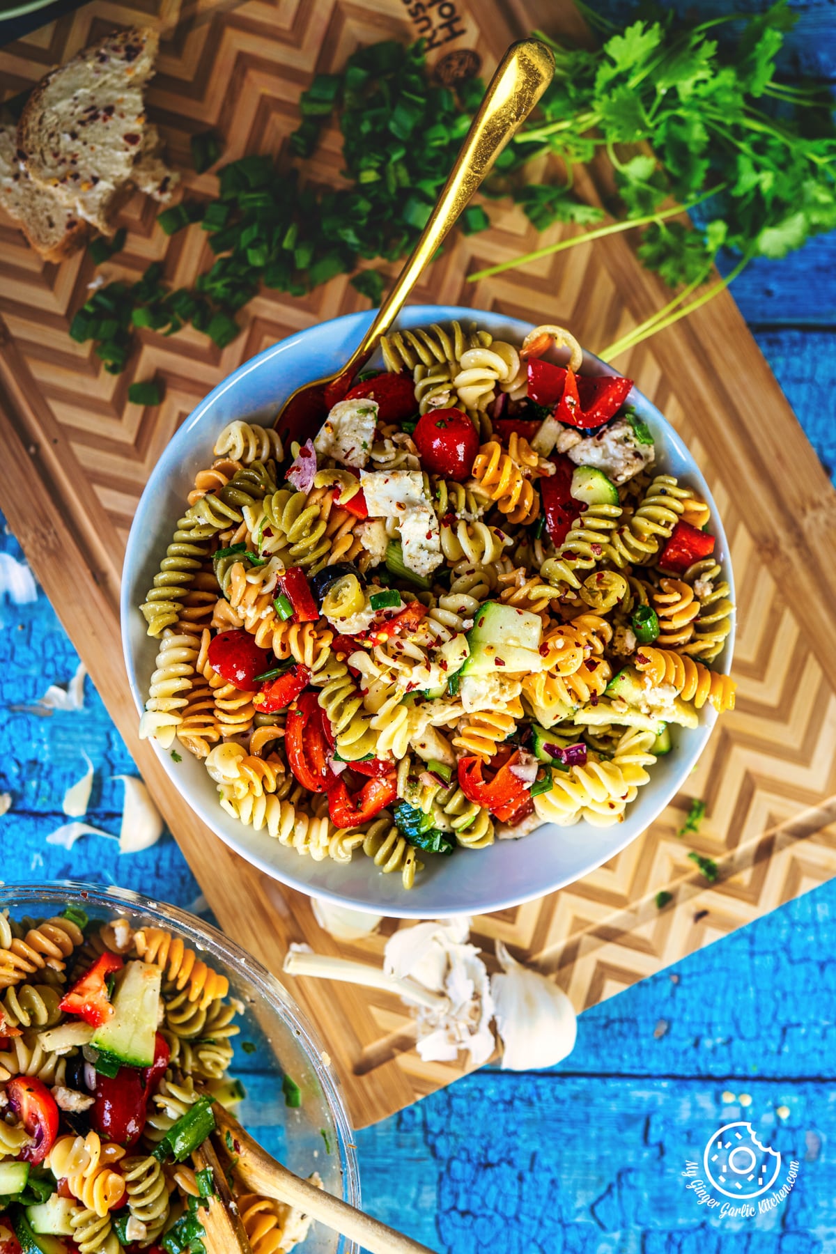 closeup photo of a bowl of pasta salad with a wooden spoon and a bowl of salad