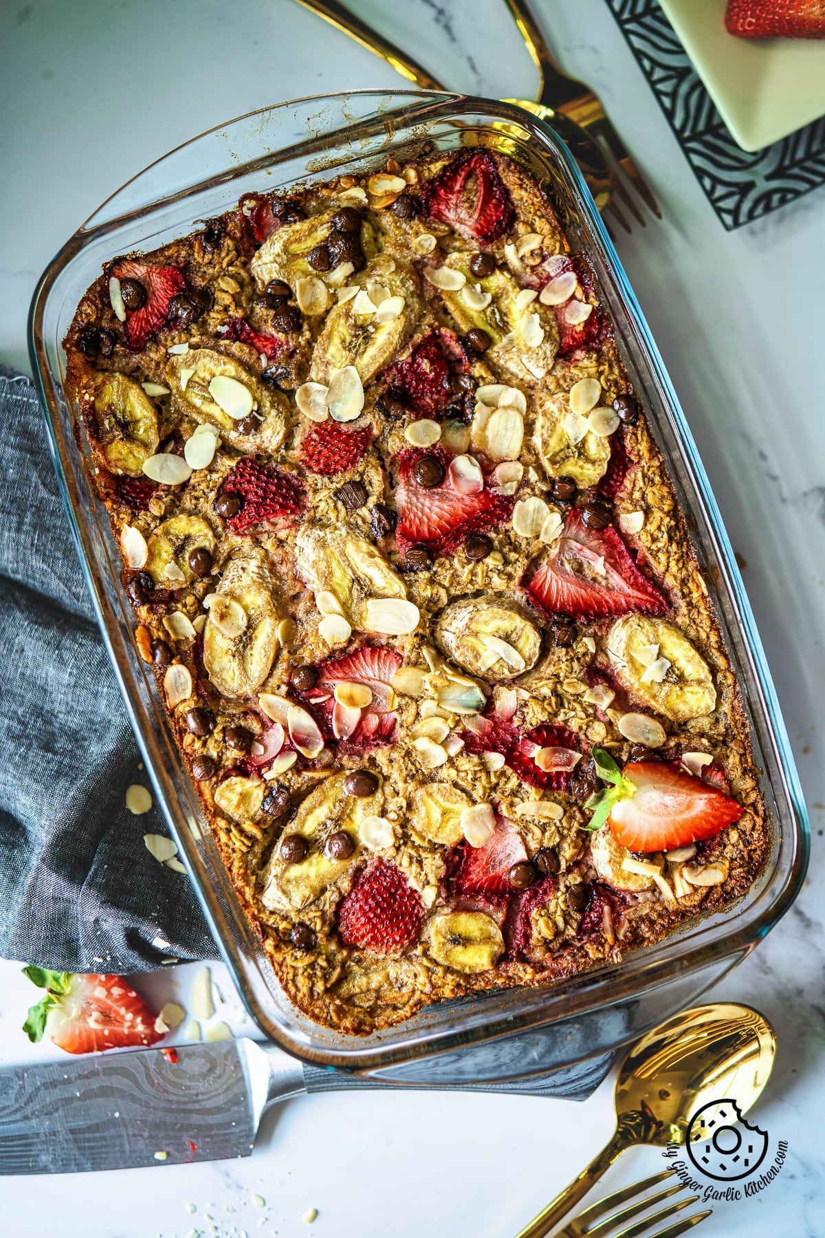 overhead closeup photo of a glass baking dish with a strawberry baked oatmeal topped with strawberries and bananas