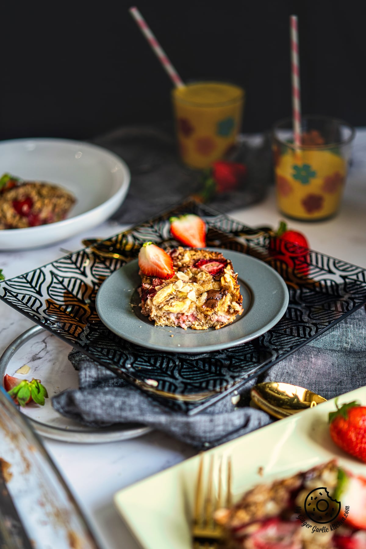 photo of a plate of strawberry baked oats with strawberries and a fork and glasses in background