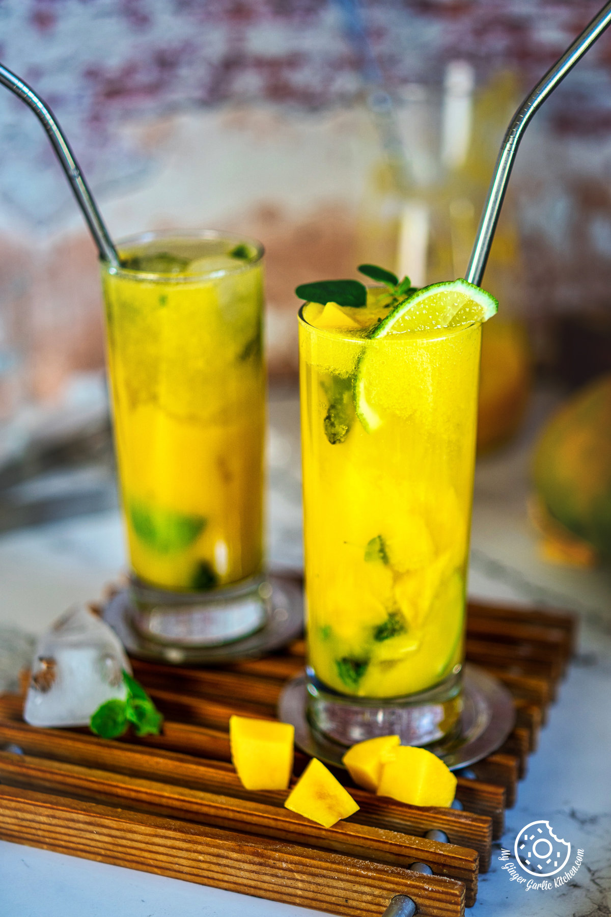 photo of two glasses of mango mojito with straws and a lime slice