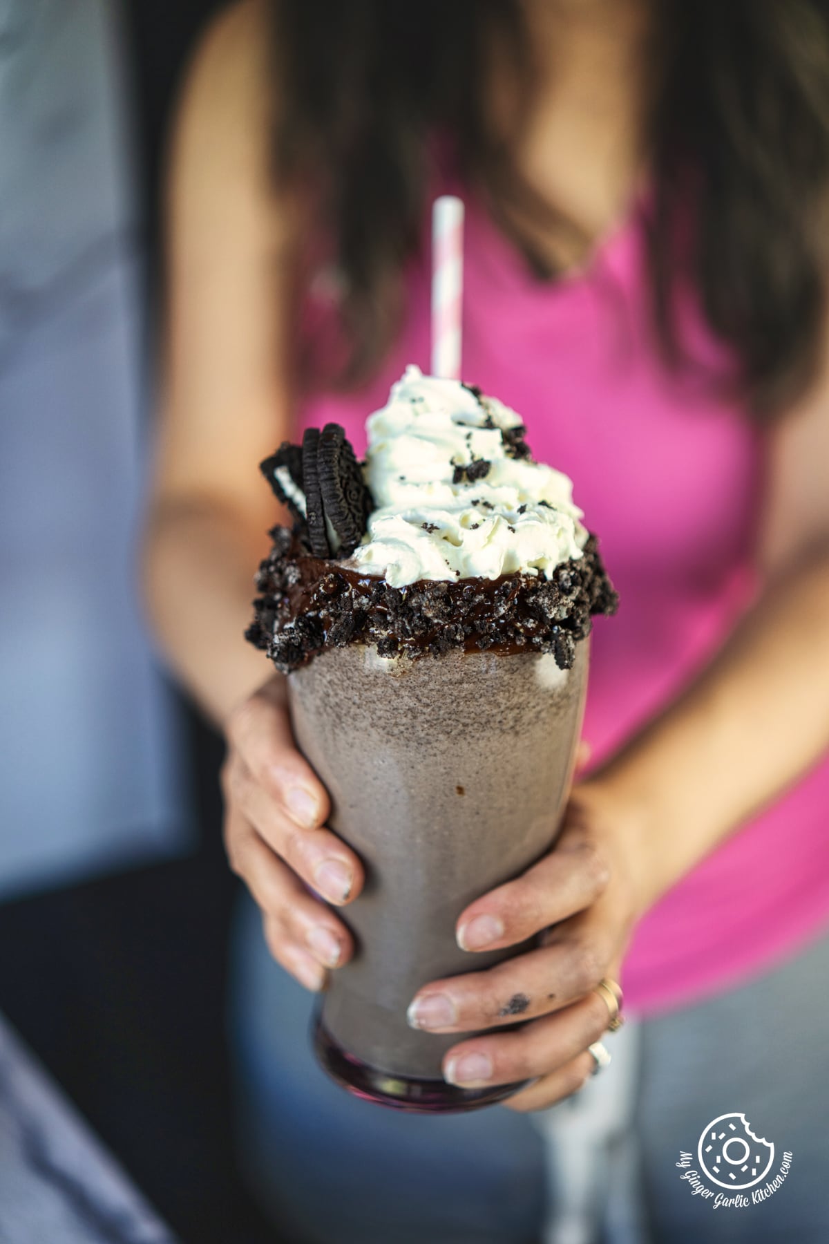 photo of a woman holding a Oreo Milkshake with whipped cream and oreo cookies