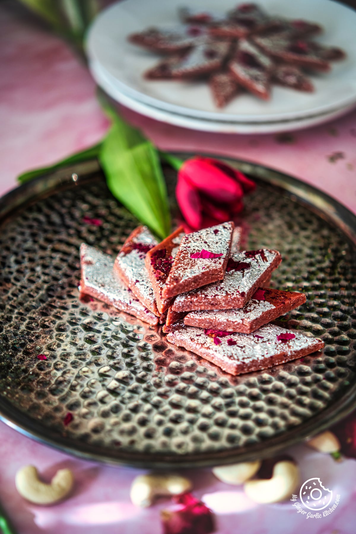 photo of a plate of kaju katli with a flower on a table