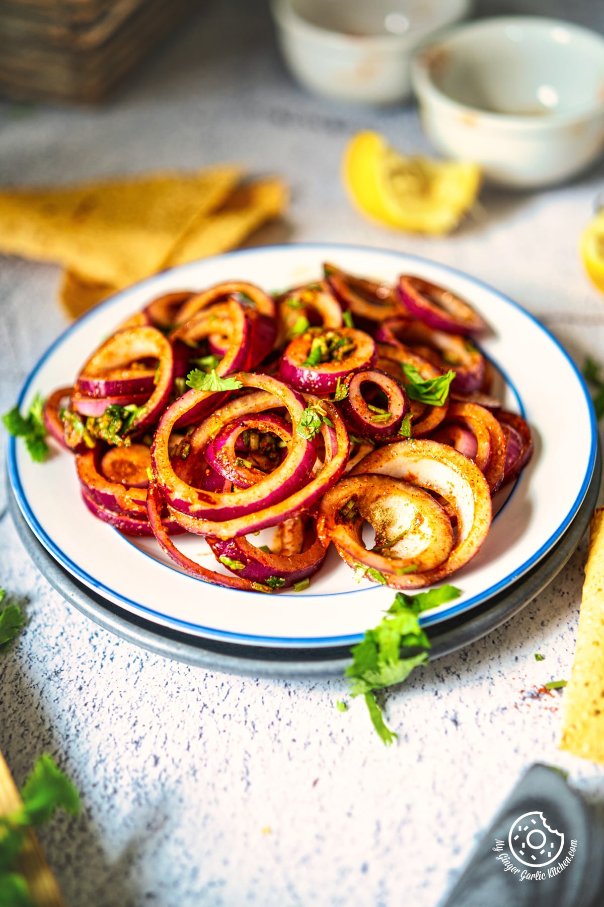 -photo of a plate of laccha onion with sliced lemons on a table